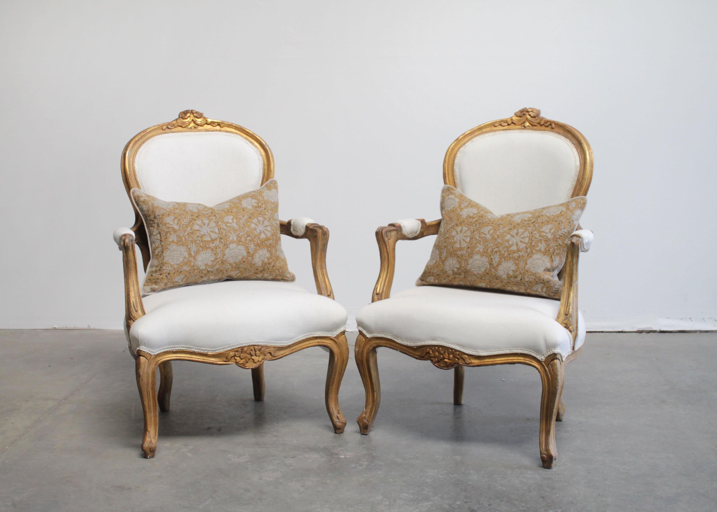 Antique Louis XV style giltwood carved open armchairs
Original giltwood finish with subtle distressed edges, and wood peeking through the gilt.
Classic cabriole legs, with flower carvings atop the center back, and floral carved apron at the seat.