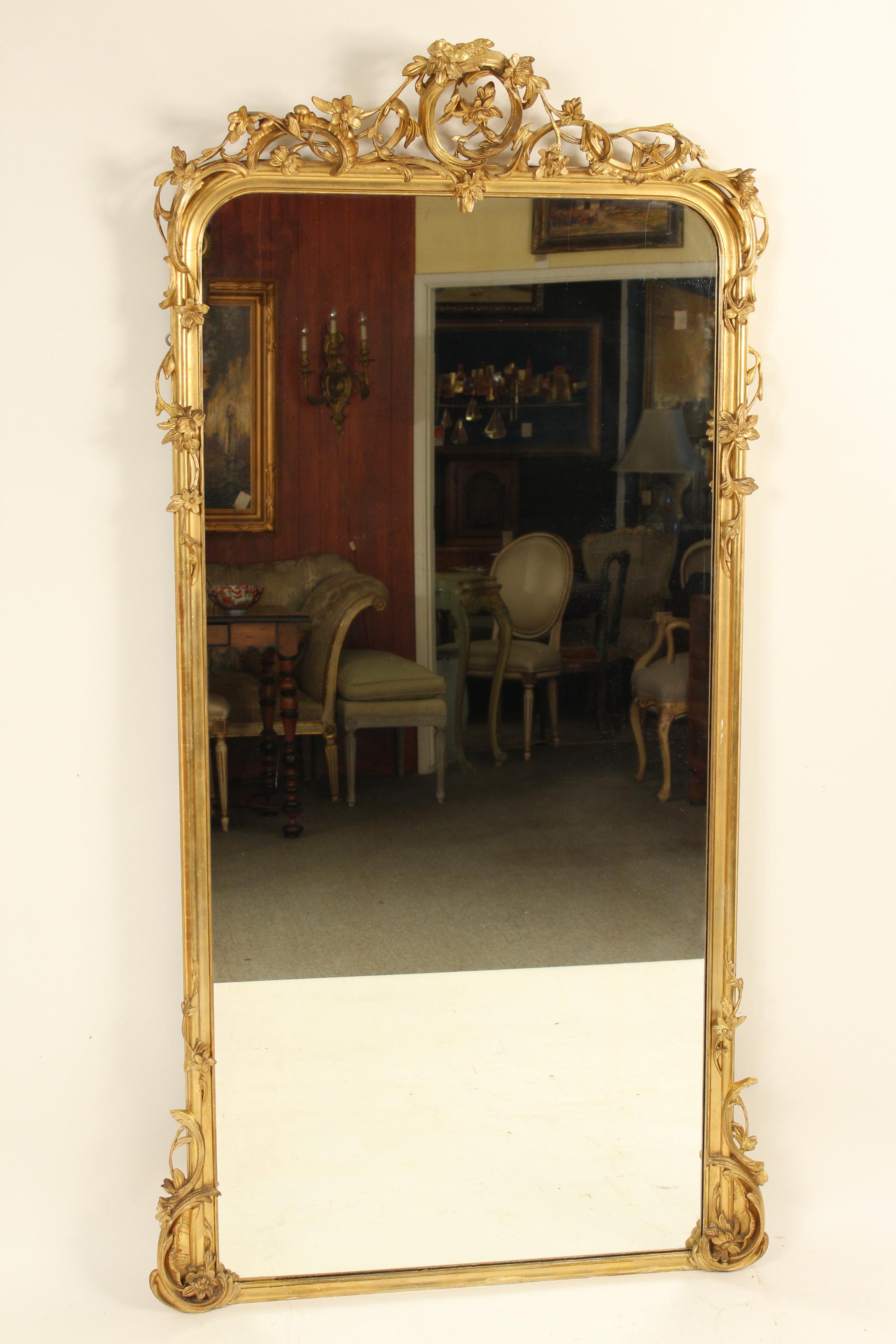 Antique Louis XV style giltwood and composition mirror with floral and c scroll designs, 19th century. This mirror has old gold leaf with some paint touch up. This mirror is very heavy and will require and professional to hang it.