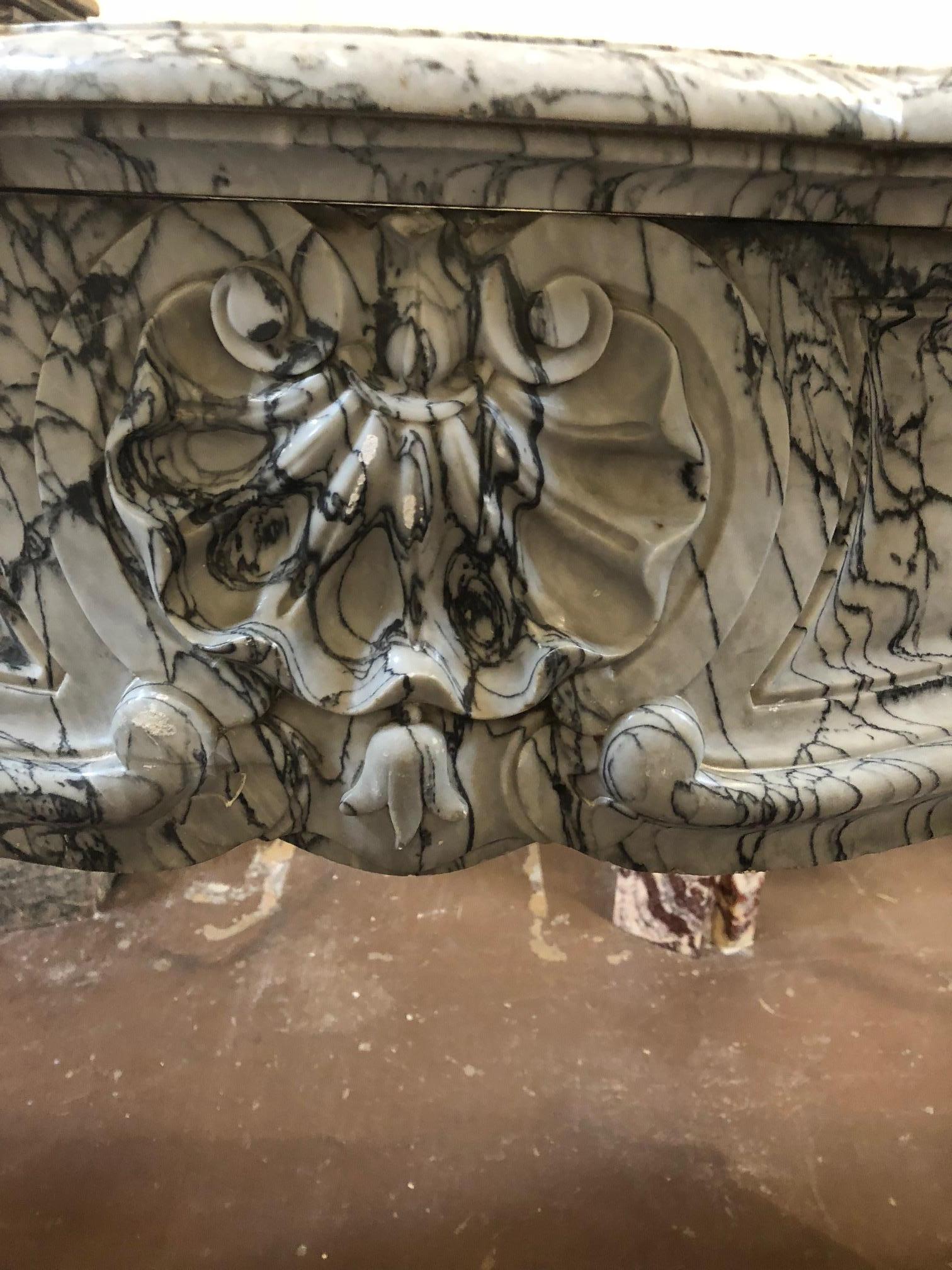 This Louis XV style fireplace with three shells in a charming grey marble was made during the 18th century. A beautiful shell with a bud adorns the centre of the frieze and scrolled carvings along delicately tapered legs.

Dimensions:
56