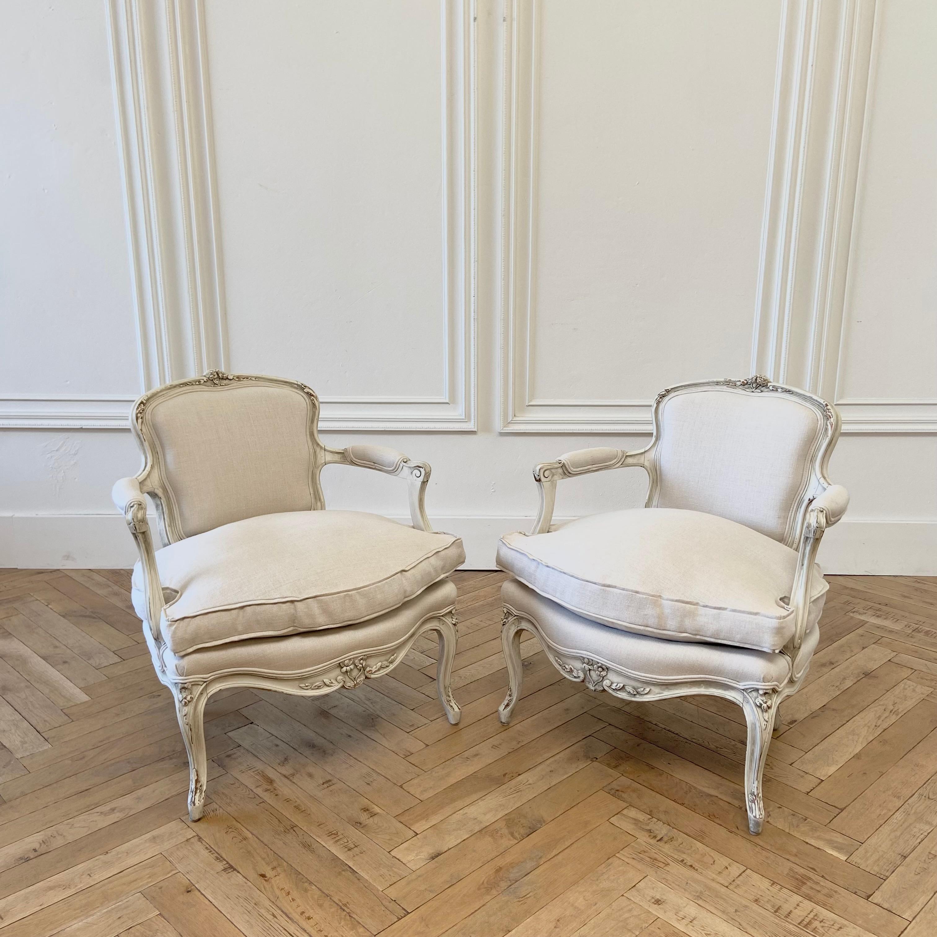 Pair of chairs 
This listing includes 2 antique Louis XV style open arm chairs.
Painted in our antique white finish, with subtle distressed edges, and antique glazed patina.
We have reupholstered these in Libeco Natural Linen. The seats have a