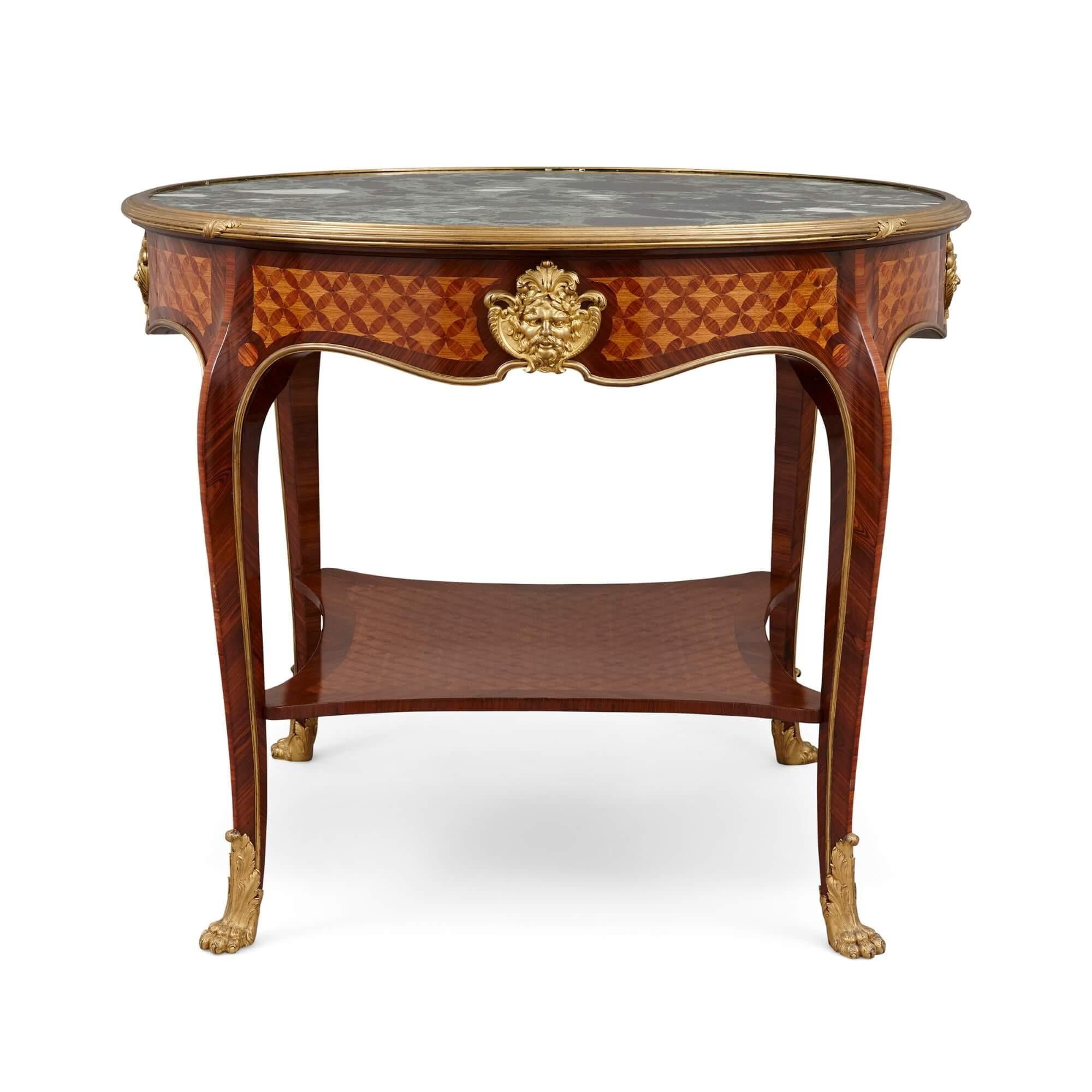 This superb piece is an antique ormolu mounted Louis XV style table, masterfully crafted with kingwood, tulipwood, and parquetry, by the famed Parisian firm L'Escalier de Cristal. The green marble top is set within a stepped surround, atop the