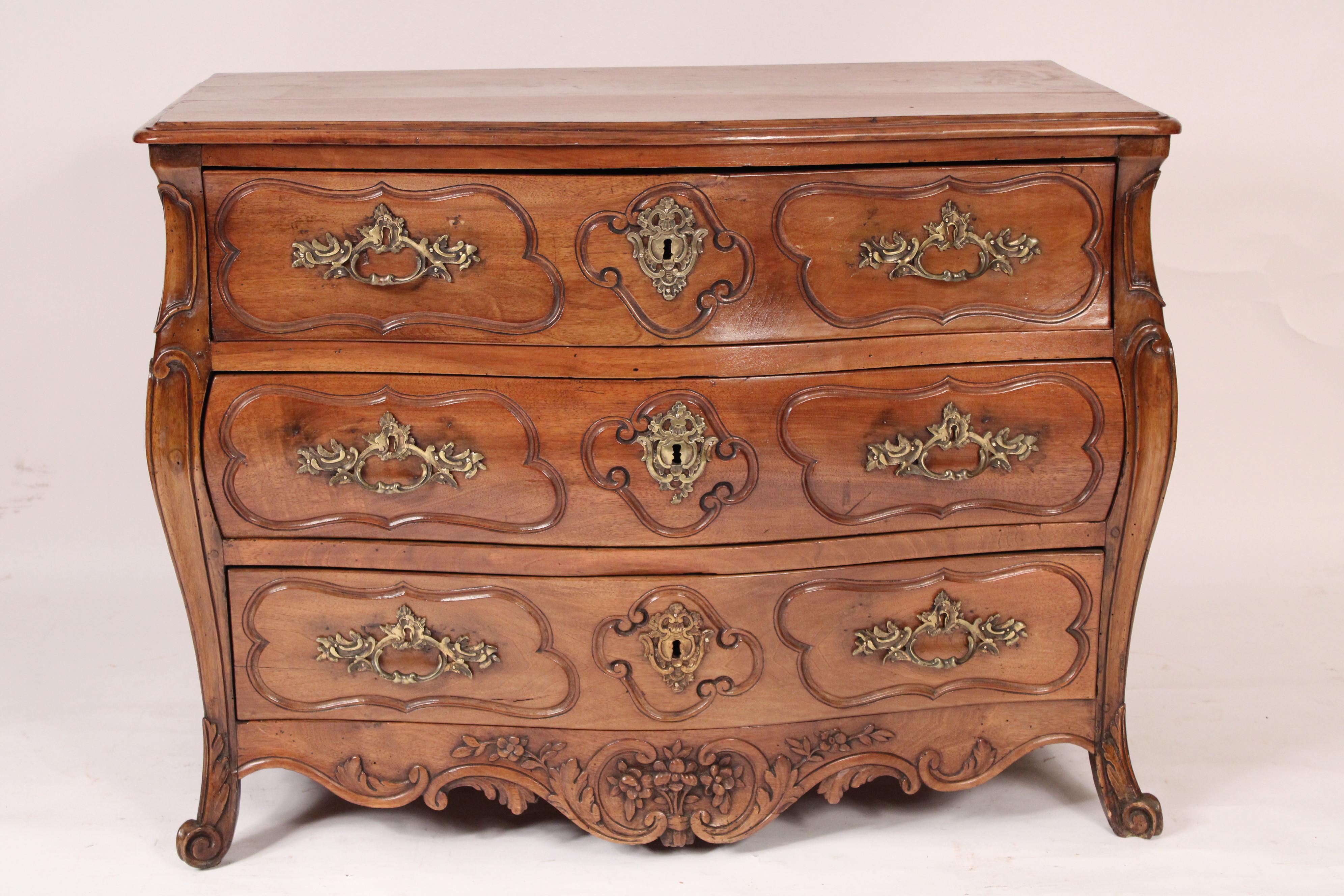 Antique Louis XV style provincial bombe walnut chest of drawers, 19th century. With a two board walnut top with thumb molded front and side edges, 3 bombe shaped drawers, rococo shaped apron with central floral carving, resting on acanthus carved