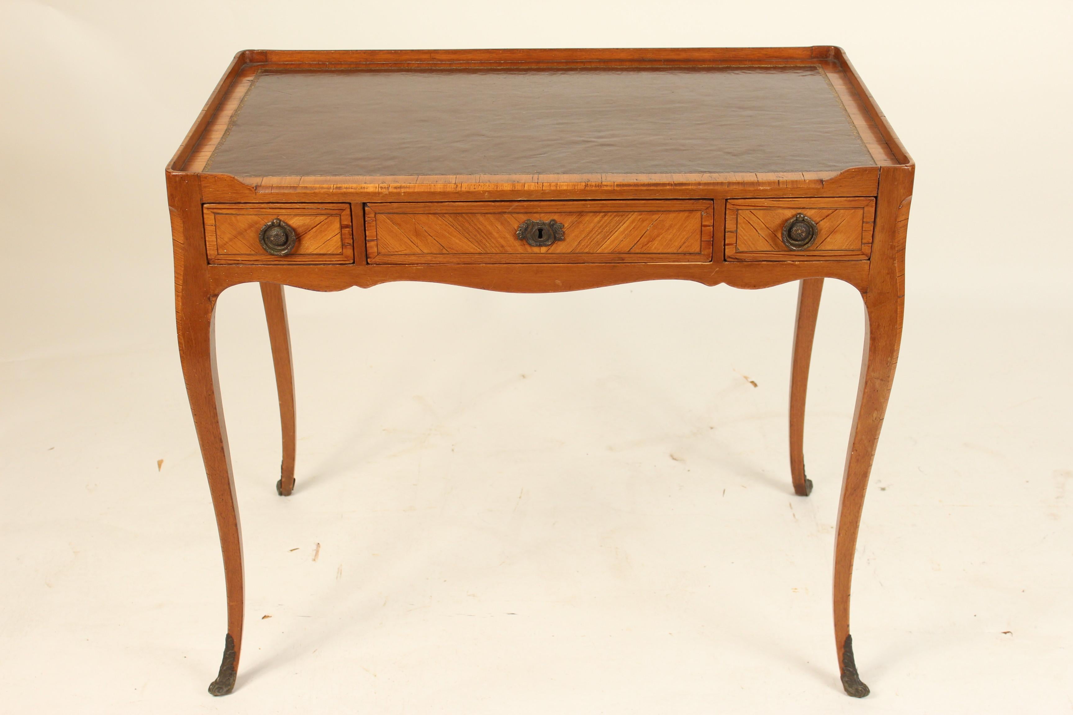 Antique Louis XV style tulip wood and beechwood writing table with a tooled leather top and bronze pulls and sabots, circa 1890-1910. Measures: Height to writing surface 29.5