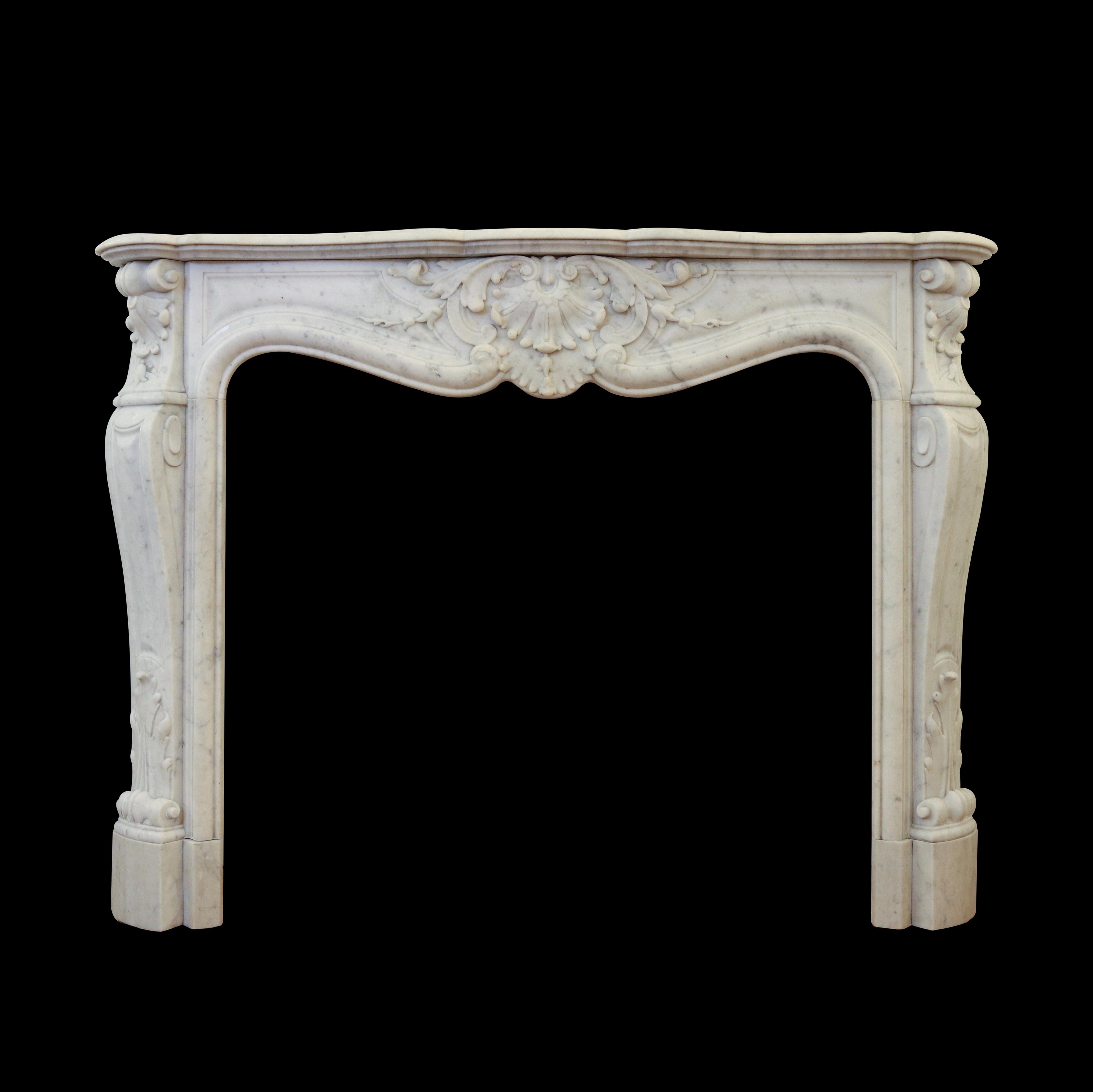 Antique Louis XV style fireplace mantel carved from white Carrara marble. The serpentine apron and angled jambs are decorated with prominent carvings of acanthus leaves, classic scrolls, and floral accents. Raised panels are carved across the apron