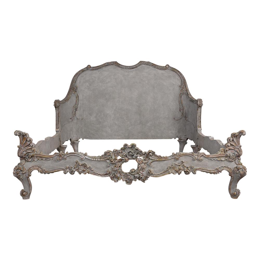 This Late 19th Century  Louis XV Style Queen Size Bed Frame fits a standard Queen sized mattress, has a solid wood frame, and is painted a pale light blue and grey color combination with a distressed finish. It features hand-carved floral details on
