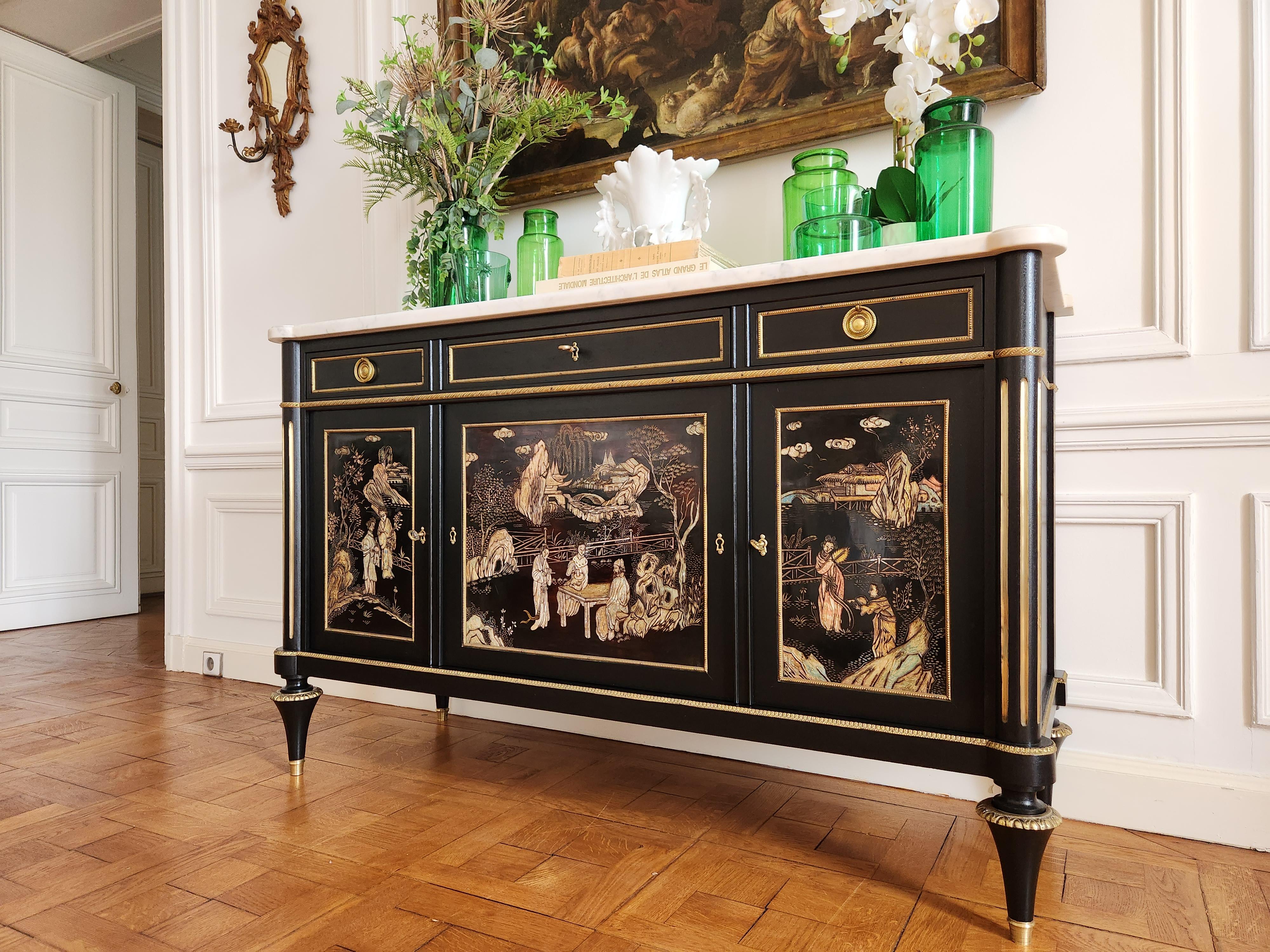 Superbo buffet antico Luigi XVI, attribuito alla Maison Jansen, rivestito in marmo bianco di Carrara, con montanti scanalati e piedi a trottola decorati con anelli e sabot in bronzo dorato. 
Tre cassetti a coda di rondine e le ante in lacca