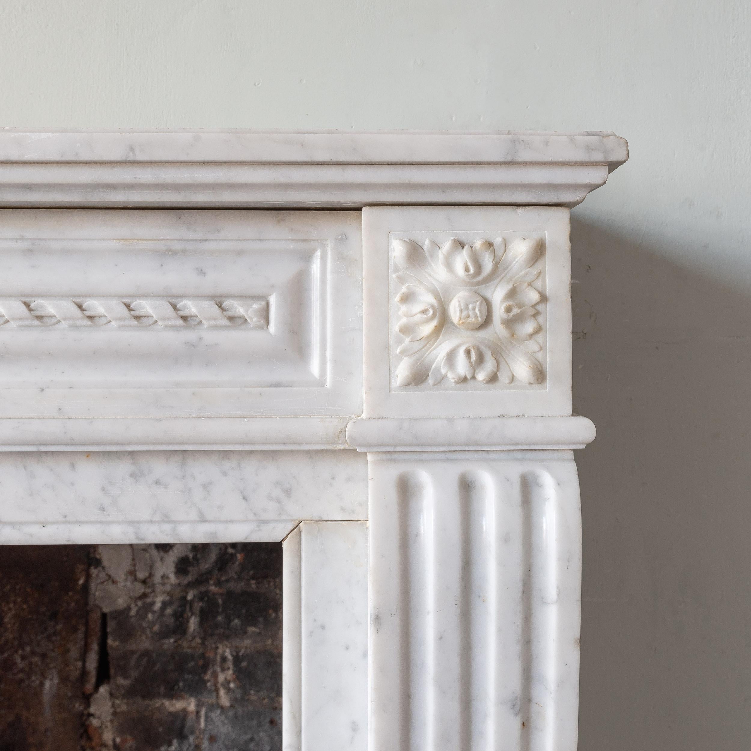 A antique French Louis XVI style Carrara marble fireplace, nineteenth century, with rope-twist frieze and scrolled jambs (sold without hearth).

Dimensions:	106cm (41¾