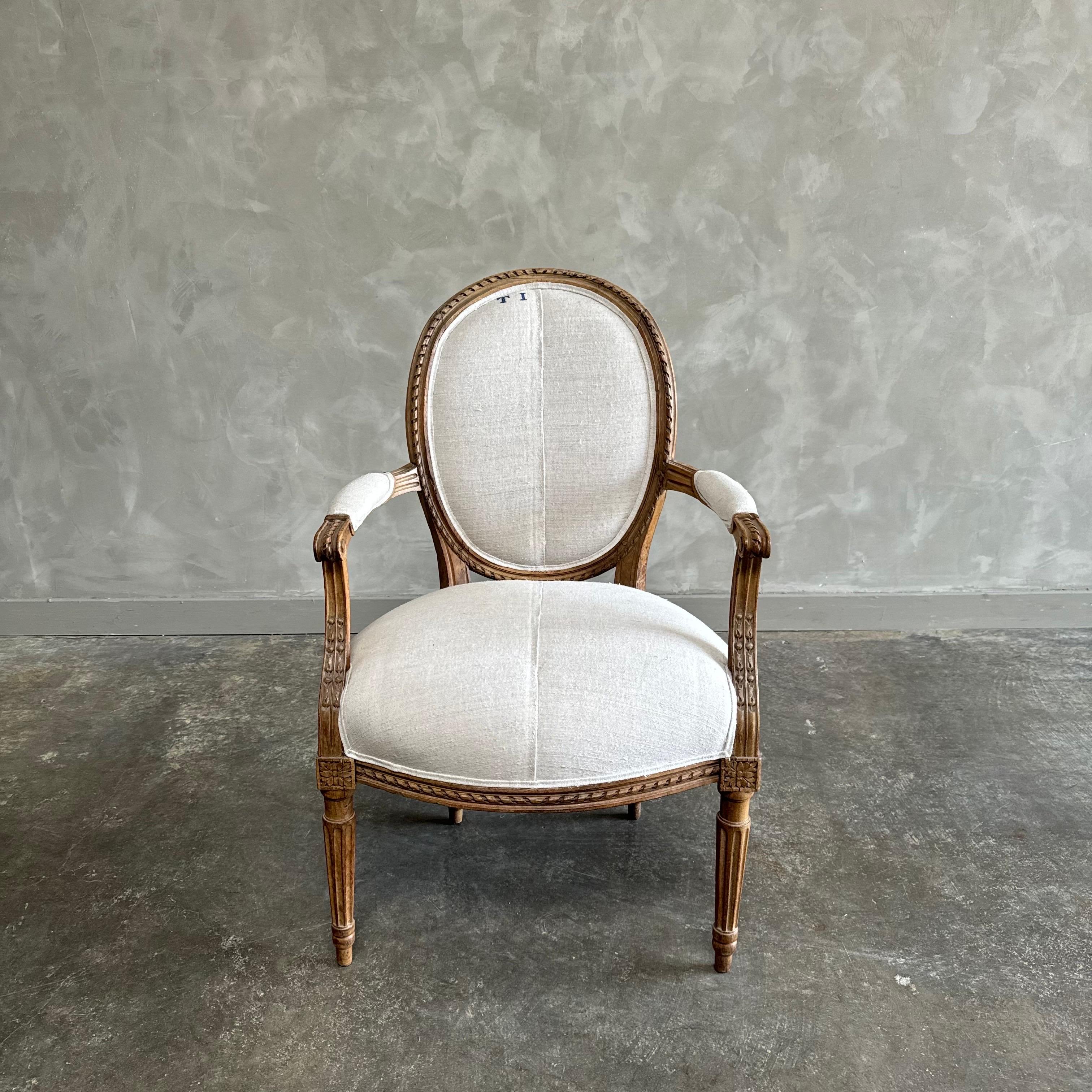 Antique gilt wood open arm chair upholstered in natural grain sack. This vintage chair has the original finish, which is a weathered patina gilt wood. We have reupholstered them in a thick, nubby grain sack that is soft to the hand. Solid and