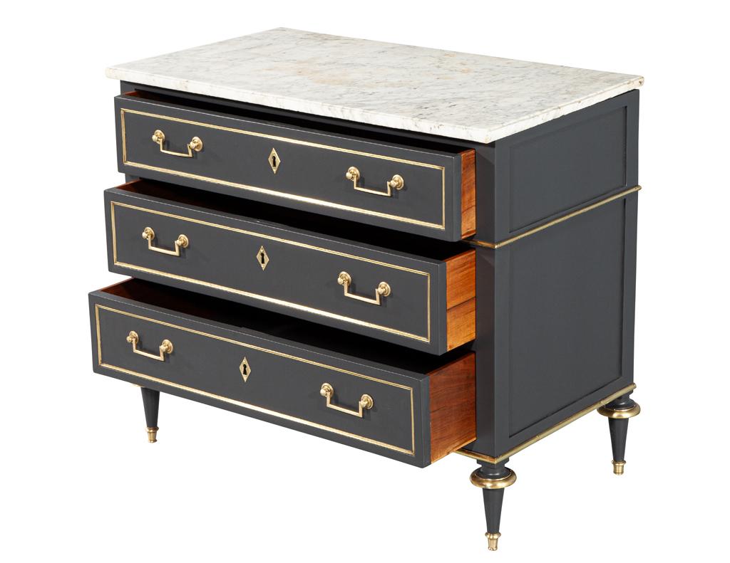 Indulge in the timeless elegance of this exquisite Louis XVI Marble Top Commode. Crafted in France, circa the 1940s. Its sleek brass inlay and hardware gleam against the sophisticated satin gray lacquered finish, creating a harmonious blend of