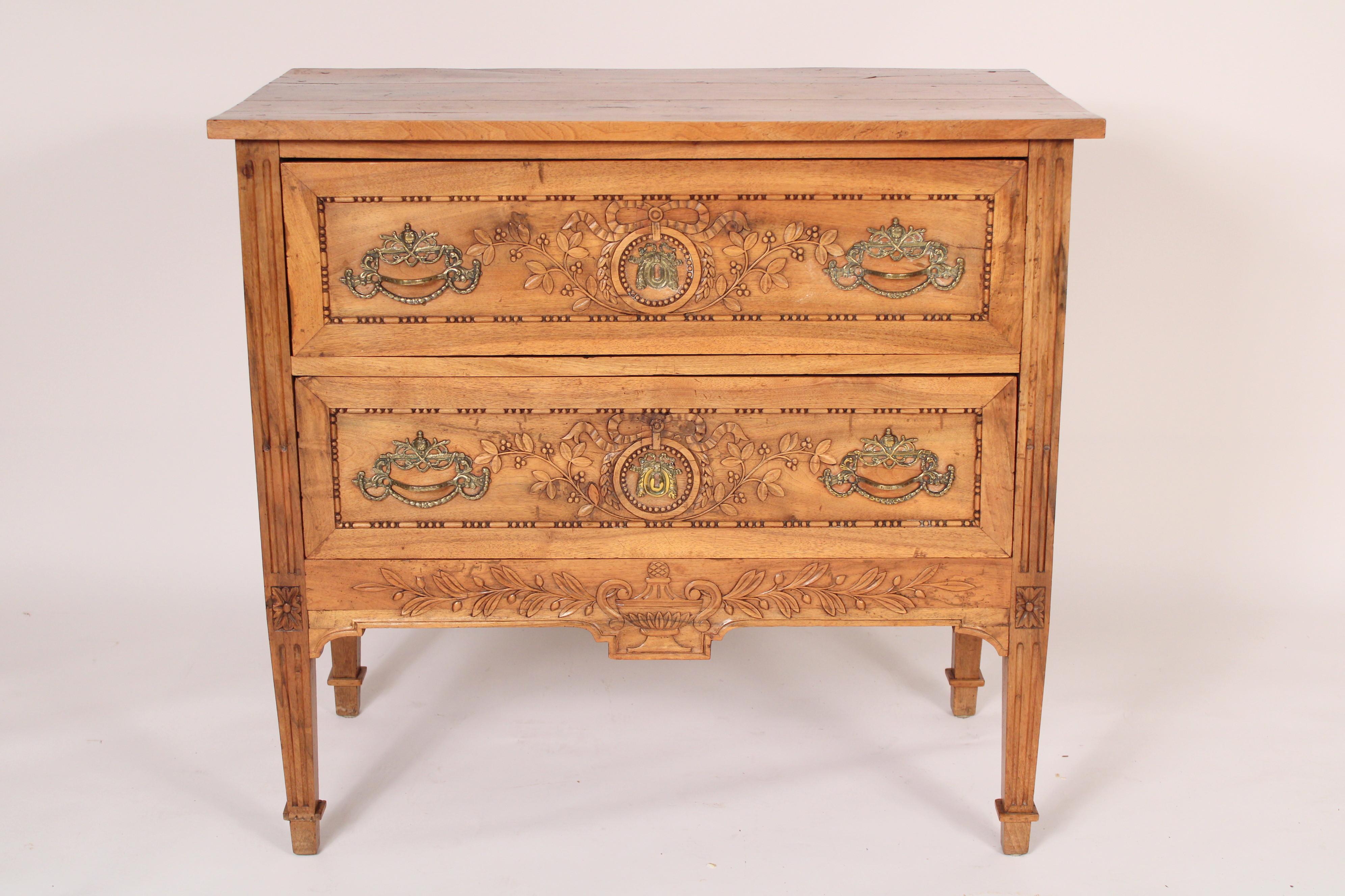 Antique Louis XVI style walnut chest of drawers, 19th century. With a rectangular 3 board top, two ribbon and leaf carved drawers resting on square fluted tapered legs.