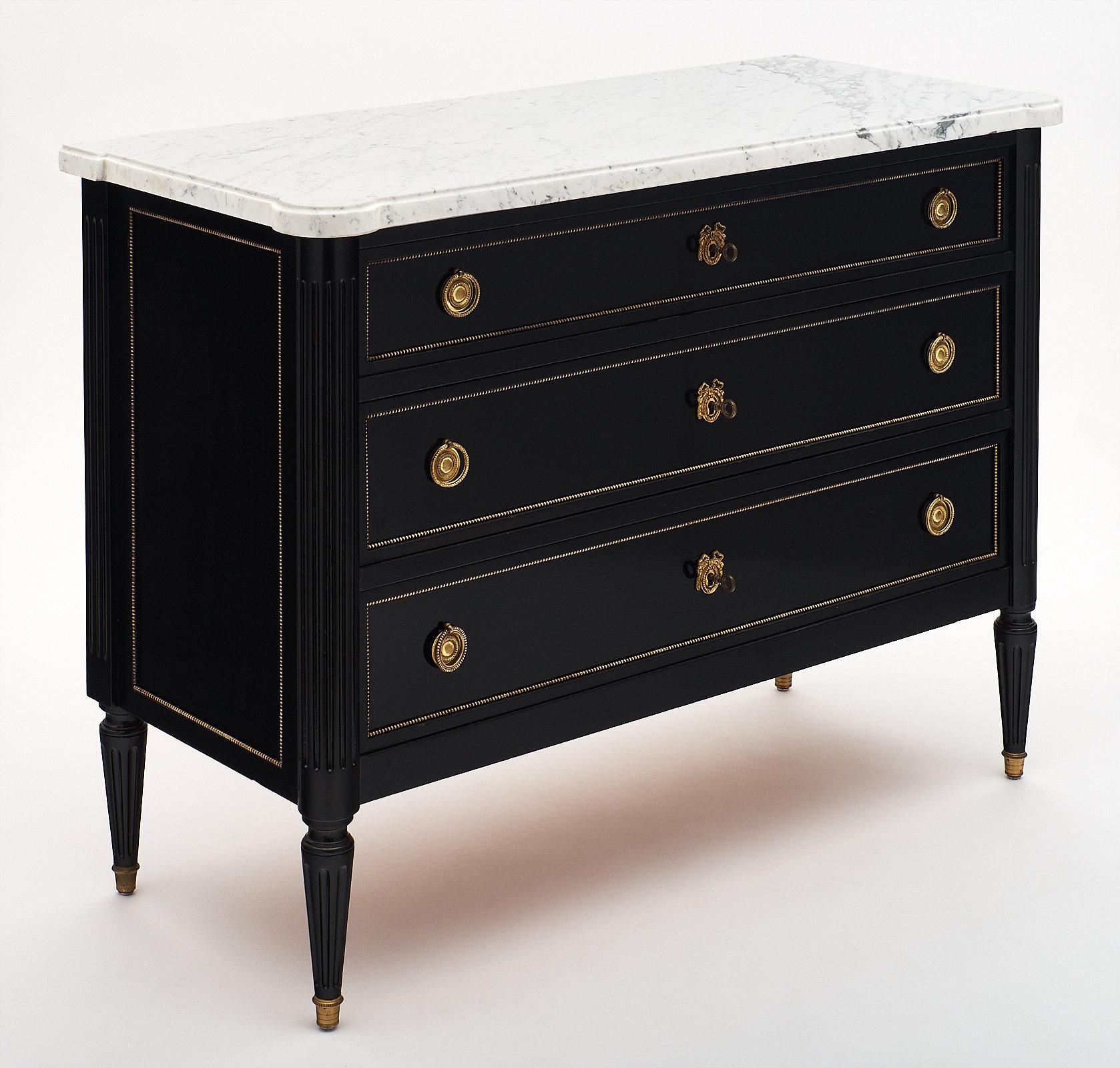 Solid Mahogany Louis XVI style antique chest of drawers, finished in an ebonized French polish. We love the intact and original Carrara marble slab. The chest has beaded trim throughout and gilded bronze hardware. We loved the three dovetailed