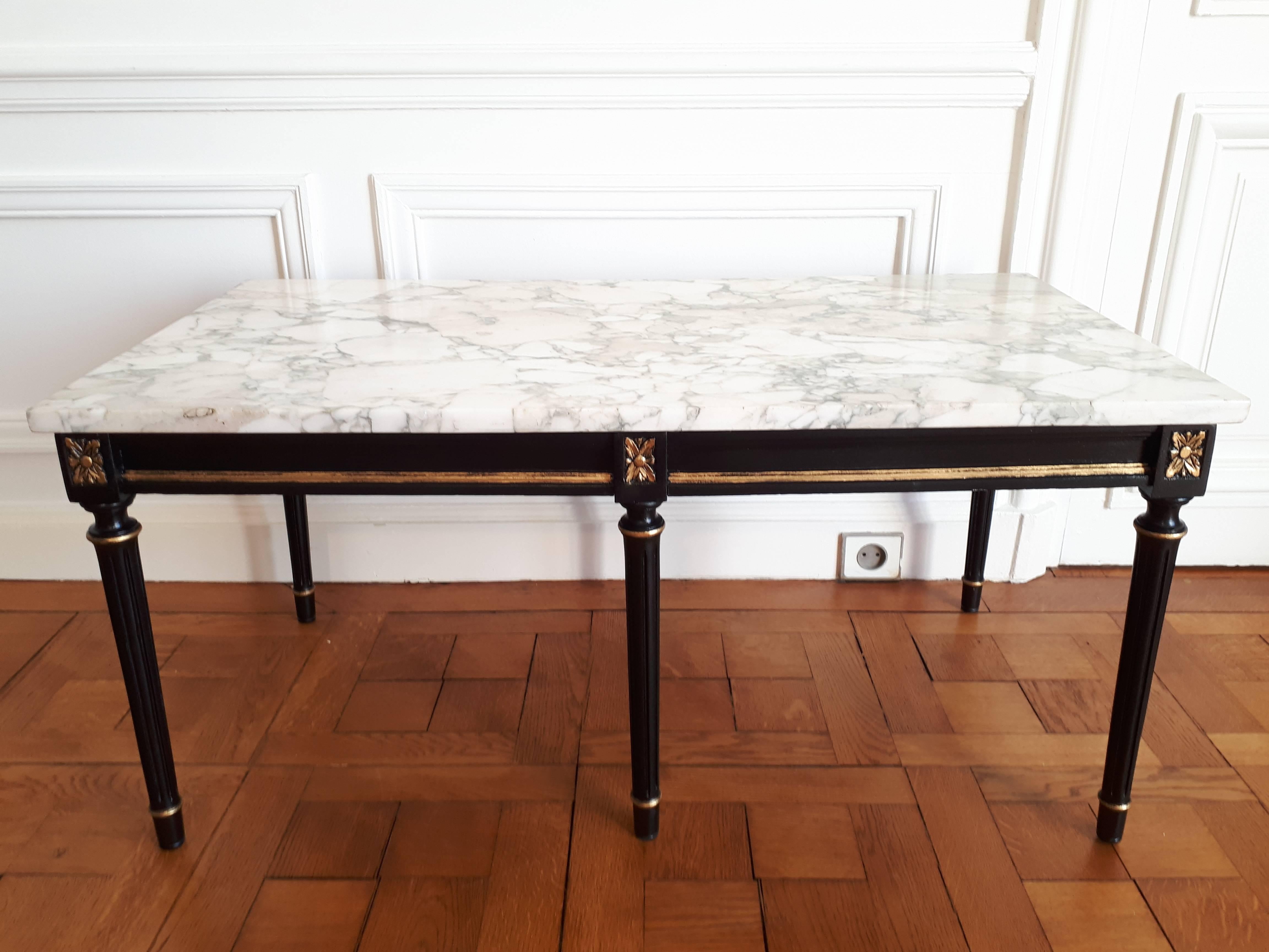 Antique coffee table with a white Carrara marble, painted wood in black and golden wax.
The 6 feet are topped with carved rosettes.