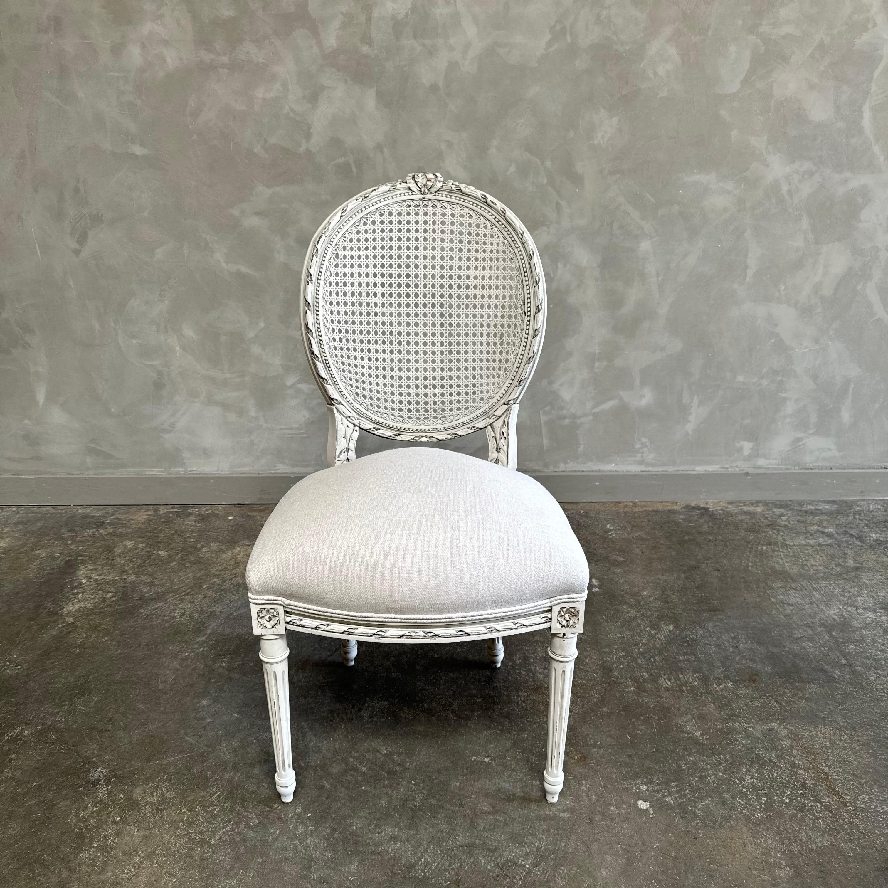 Antique French Louis XVI Style Cane chair painted in a french oyster white finish with subtle distress edges, finished with an antique patina. Cane back, solid and sturdy ready for everyday use.
Cane in good strong condition. Antique chair 20”w x