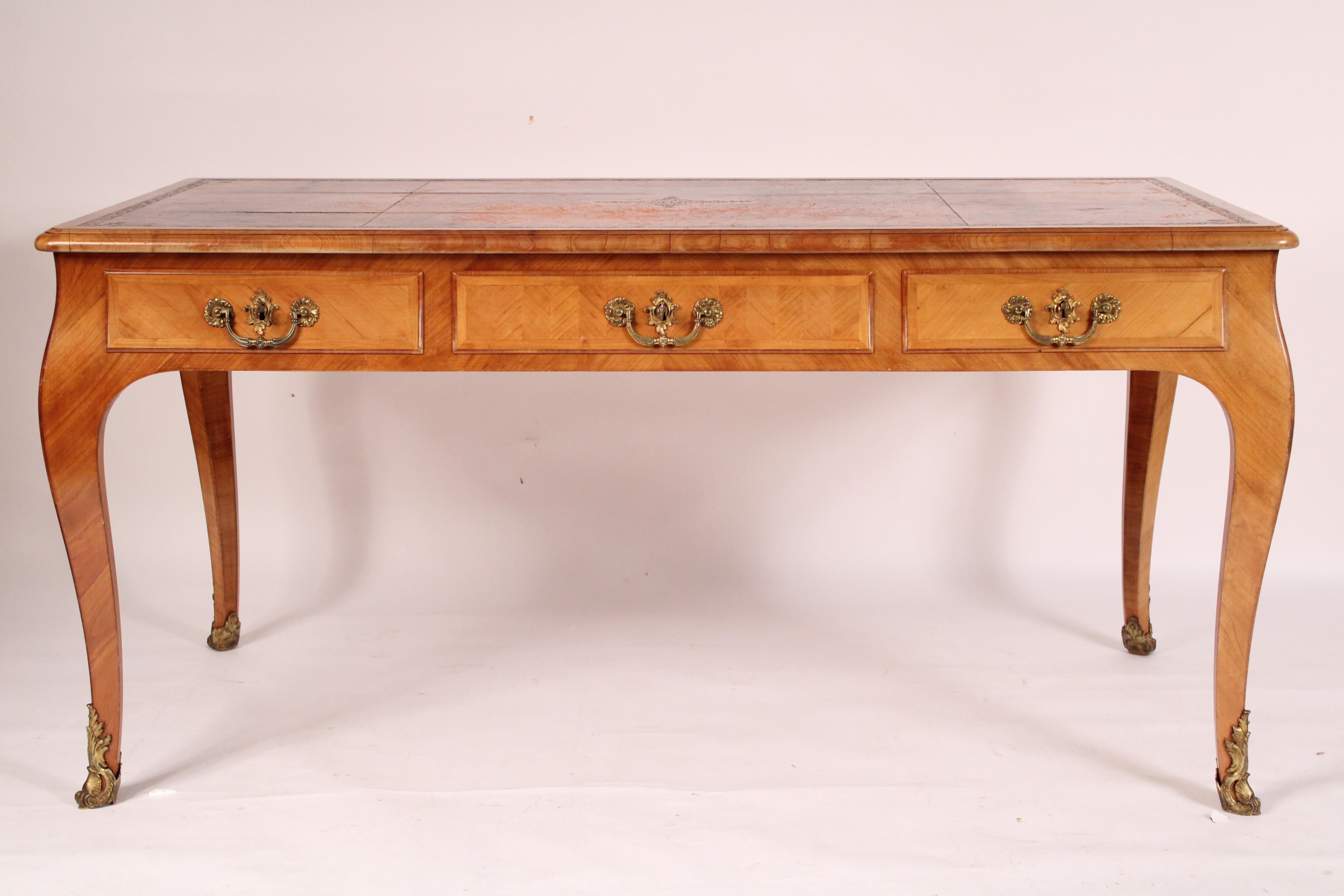 Antiguo escritorio de madera de frutal estilo Luis XV con monturas de latón y tapa de cuero, hacia 1900. Con encimera rectangular de esquinas redondeadas, inserto de cuero, 3 cajones de friso con herrajes de latón, apoyados sobre patas cabriolé