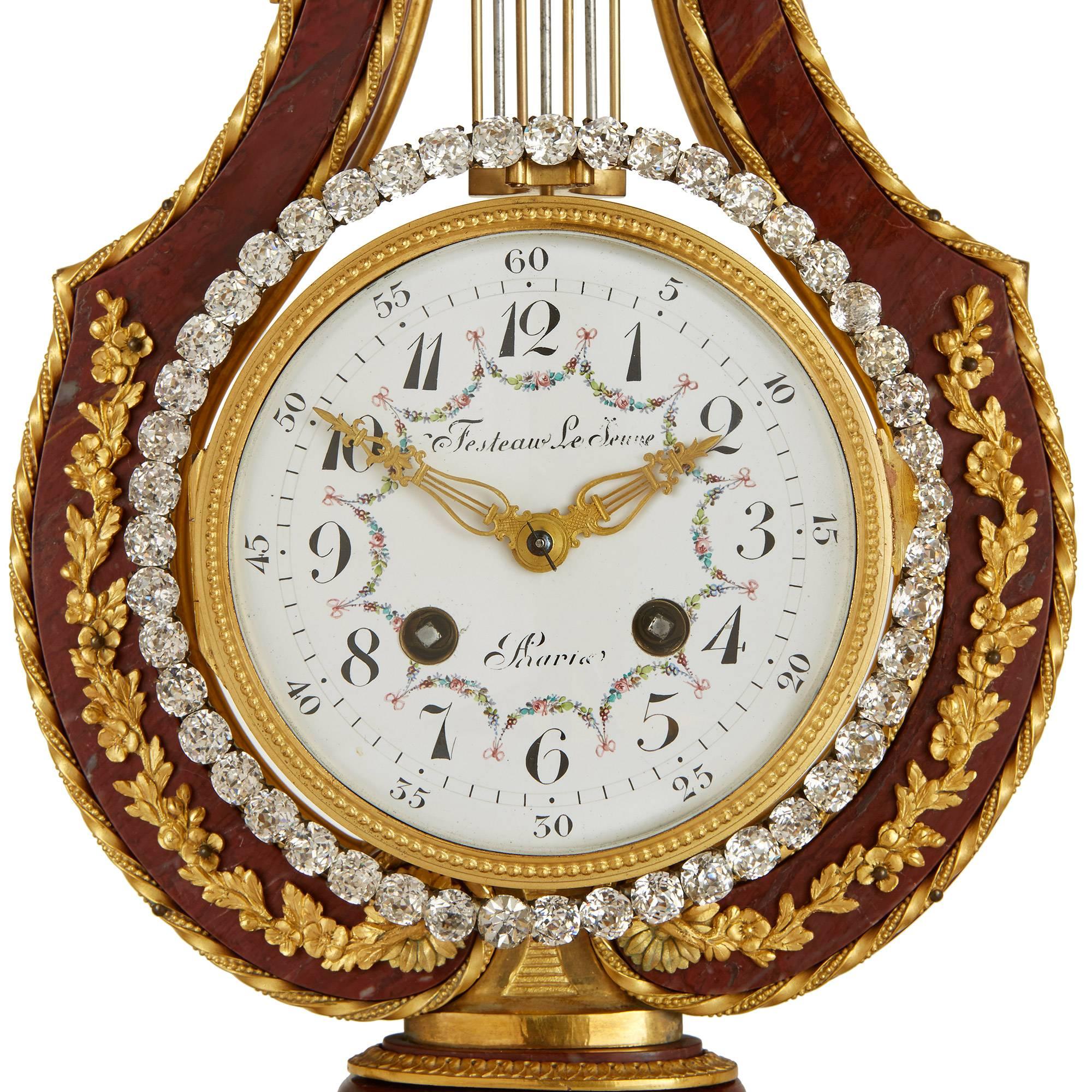 Dieses majestätische, dreiteilige Uhrenset ist ein wahrer Augenschmaus und besticht durch den schönen Kontrast zwischen rotem Marmor, vergoldeter Bronze und glitzernden Juwelen. Das Set besteht aus einer zentralen Uhr und einem Paar flankierender
