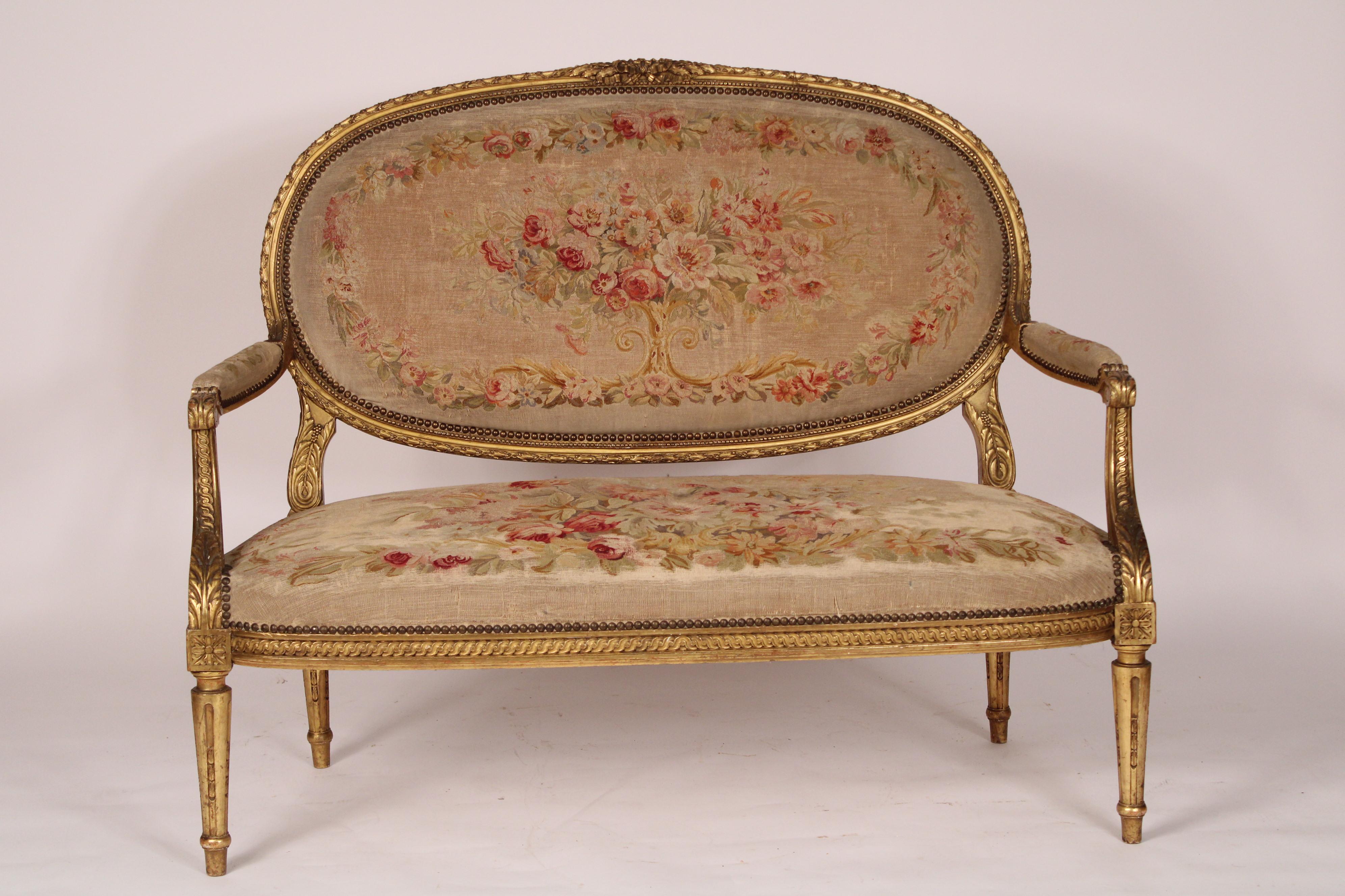 Antique Louis XVI style gilt wood settee with Aubusson style upholstery, circa 1900. The back with Aubusson style upholsterery with a foliate carved gilt wood frame, an Aubusson upholstered seat, gilt wood down swept arms with acanthus and guilloche