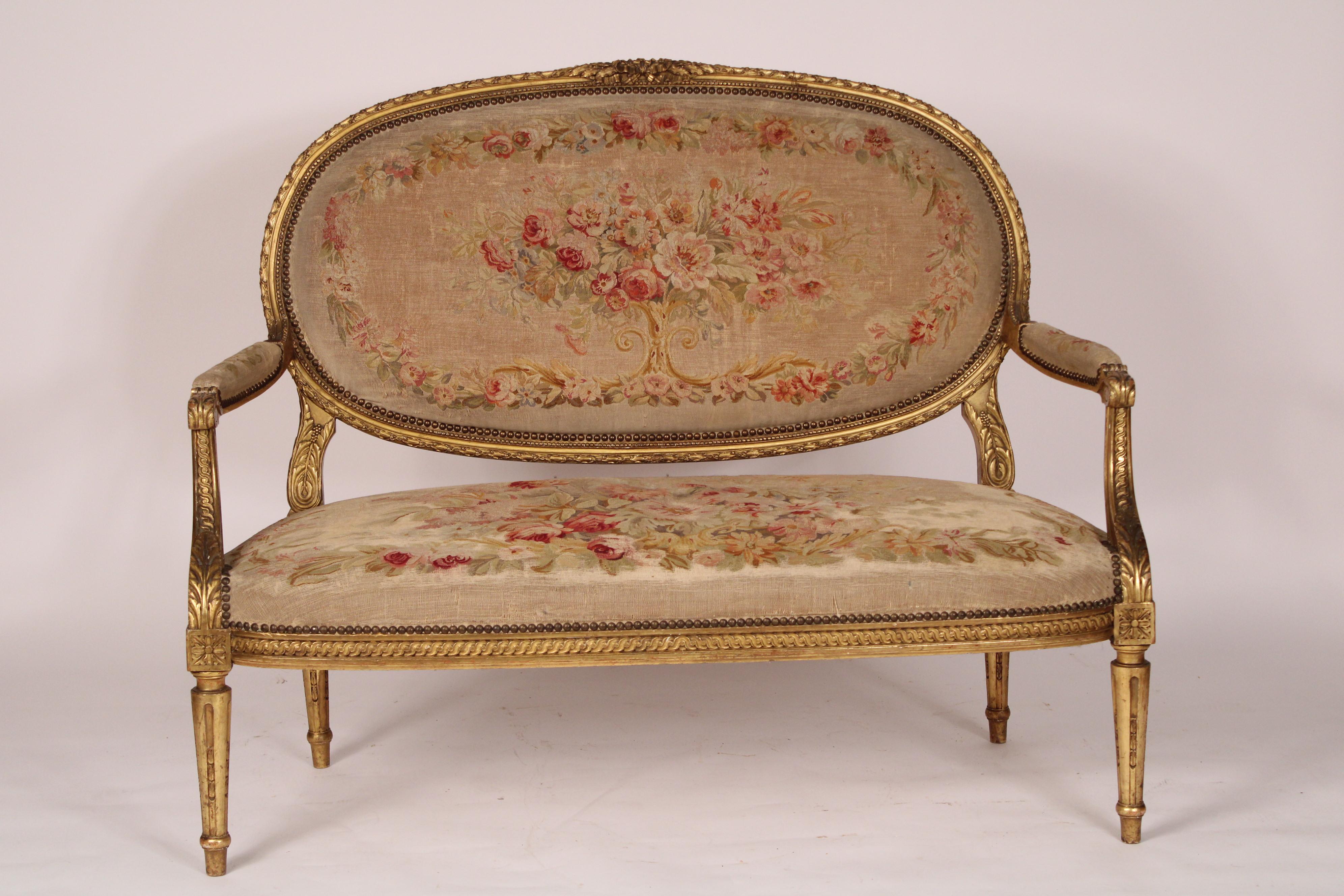 Canapé ancien en bois doré de style Louis XVI avec tapisserie de style Aubusson, vers 1900. Le dossier est recouvert d'une tapisserie de style Aubusson avec un cadre en bois doré sculpté de feuillages, un siège recouvert d'Aubusson, des accoudoirs