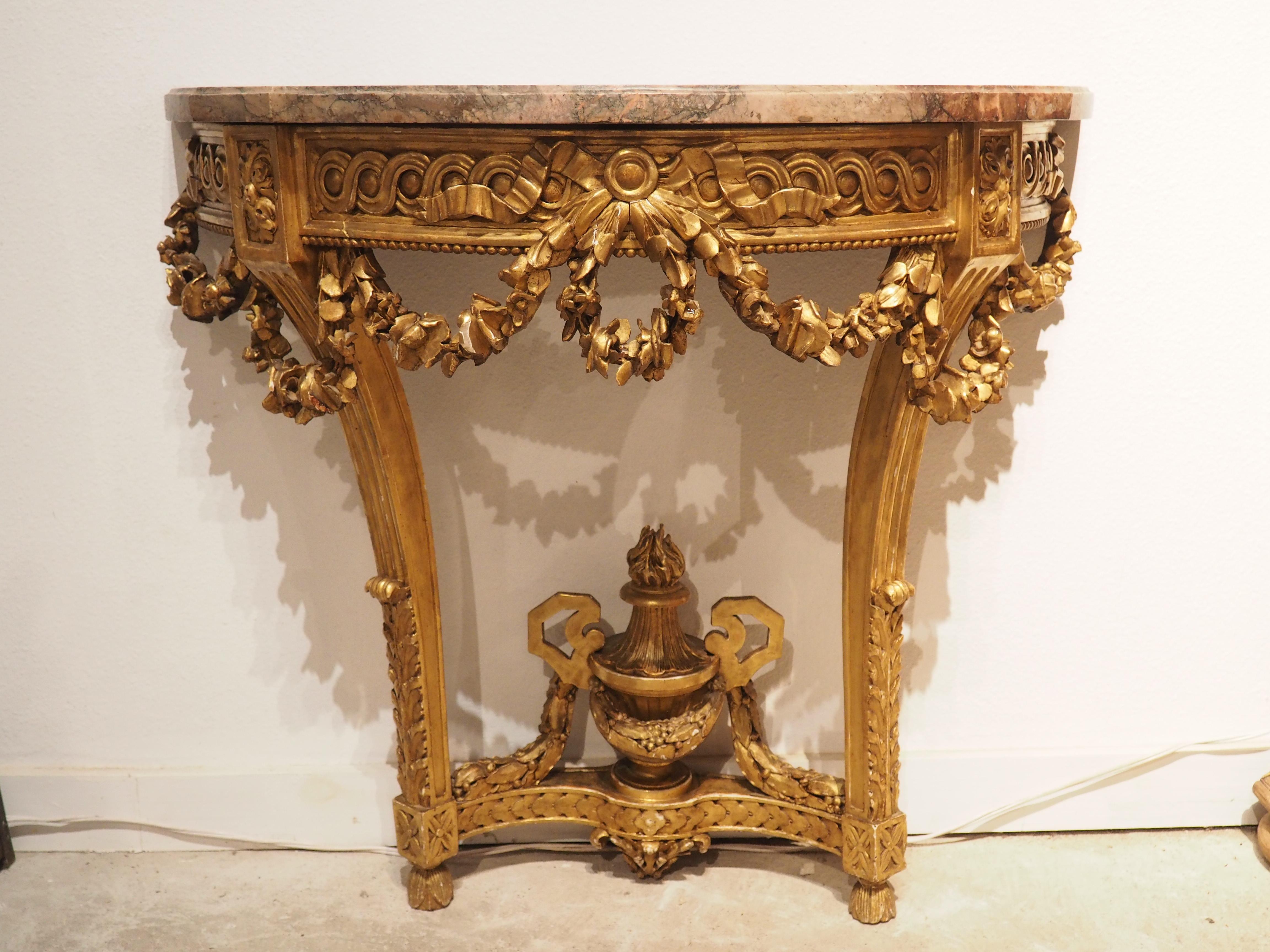 Topped by a beautiful striated Flandres Rouge marble, this giltwood console from circa 1860 was hand-carved with Louis XVI style motifs. The one inch thick red, pink, beige, brown, and gray marble has a chamfered edge. It has been carved with two