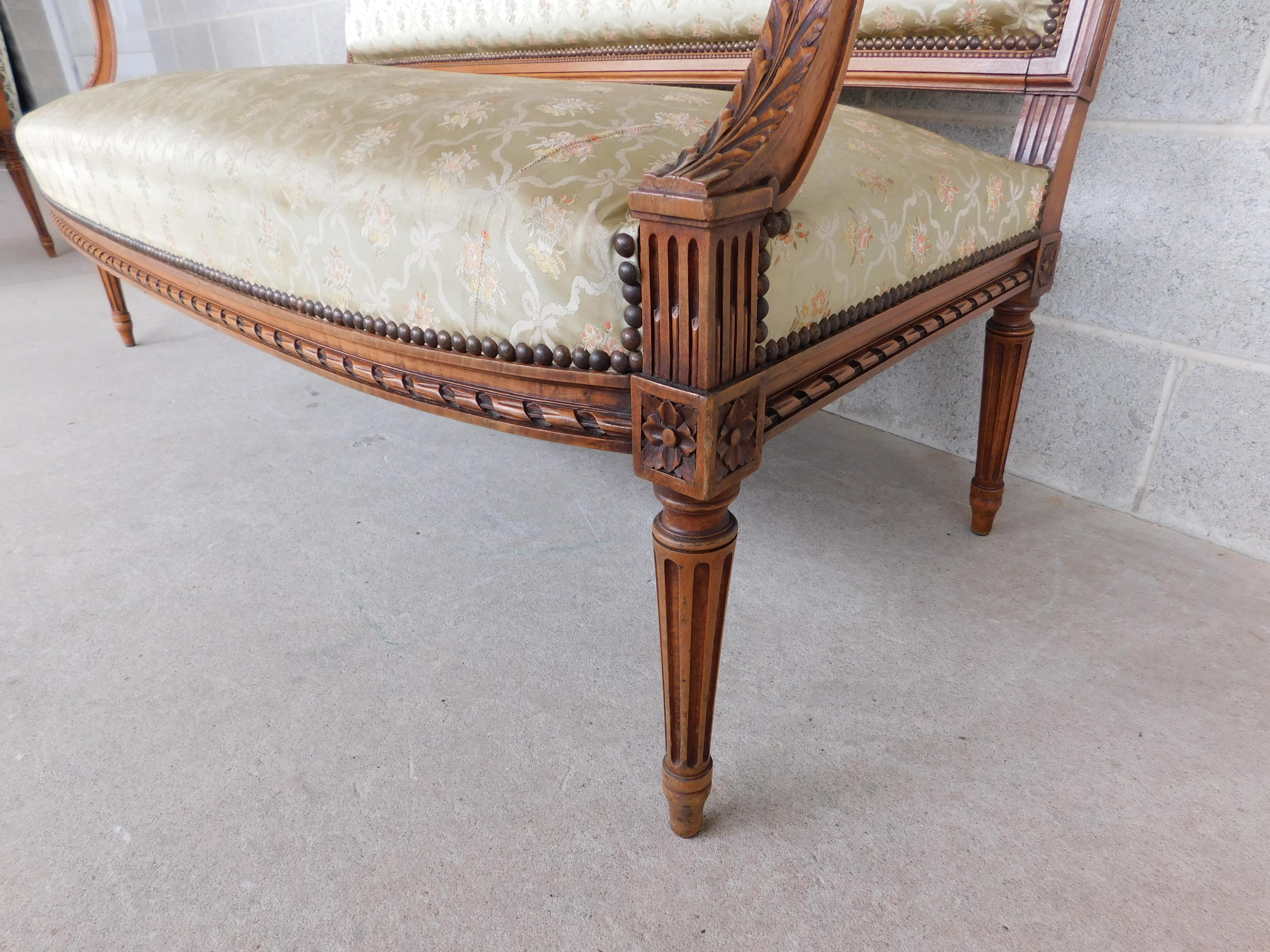 French Settee & Pair of Louis XVI style armchairs from the Late 19th century. These antique oak framed chairs & settee, with upholstered centers set within a highly carved vertical acanthus leaf Top Rail, and Side Post of the frame. The padded arms
