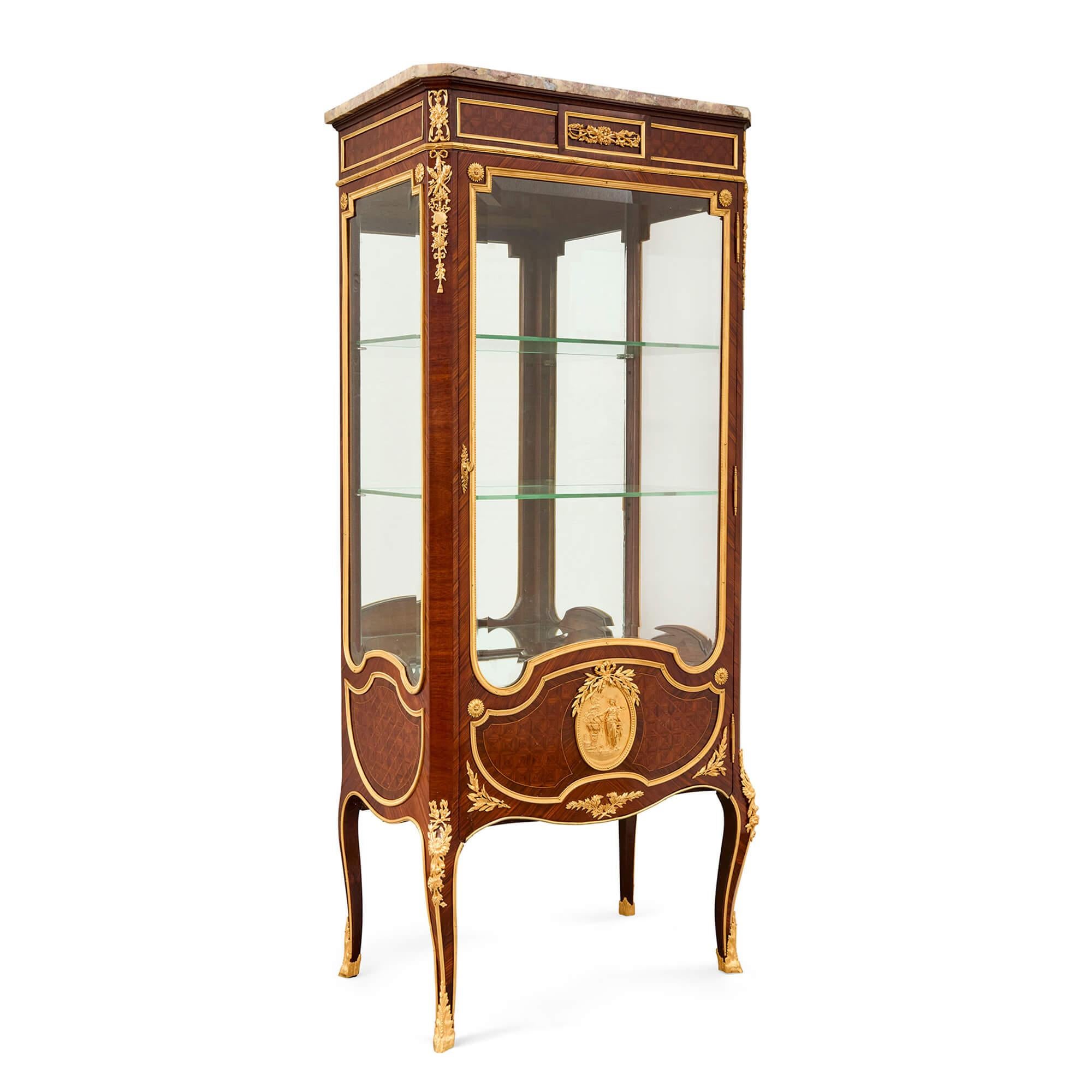 Antica vetrinetta in stile Luigi XVI in ormolu, marmo e parquet 
Francese, fine del XIX secolo  
Altezza 158cm, larghezza 68cm, profondità 40cm 

Realizzata alla fine del XIX secolo in Francia, questa splendida vetrina presenta un design elegante e