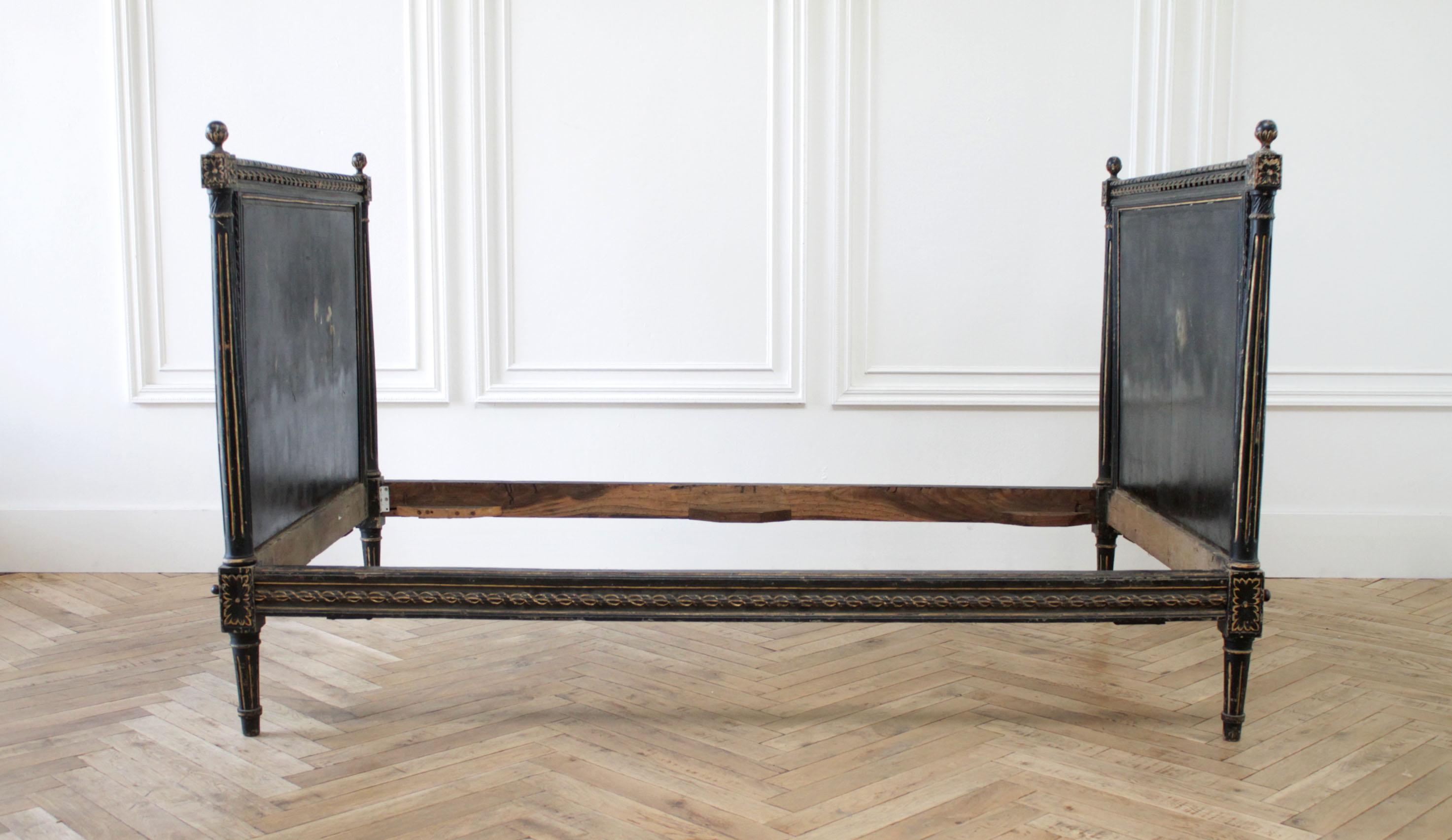 Antique Louis XVI style painted French daybed
Original black paint with faded and distressed patina. Original rails, one rail is a decorative rail with carvings that would be showing and the other is a plain rails which would've been placed against