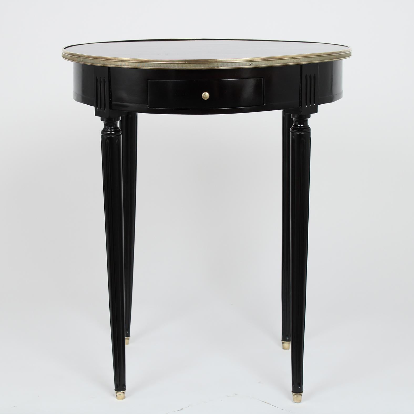 This antique French Louis XVI style side table has been restored and newly stained in an ebonized color with a lacquered finish. The top has brass molding details around the top, a single drawer with a brass knob in the front, and a small pullout