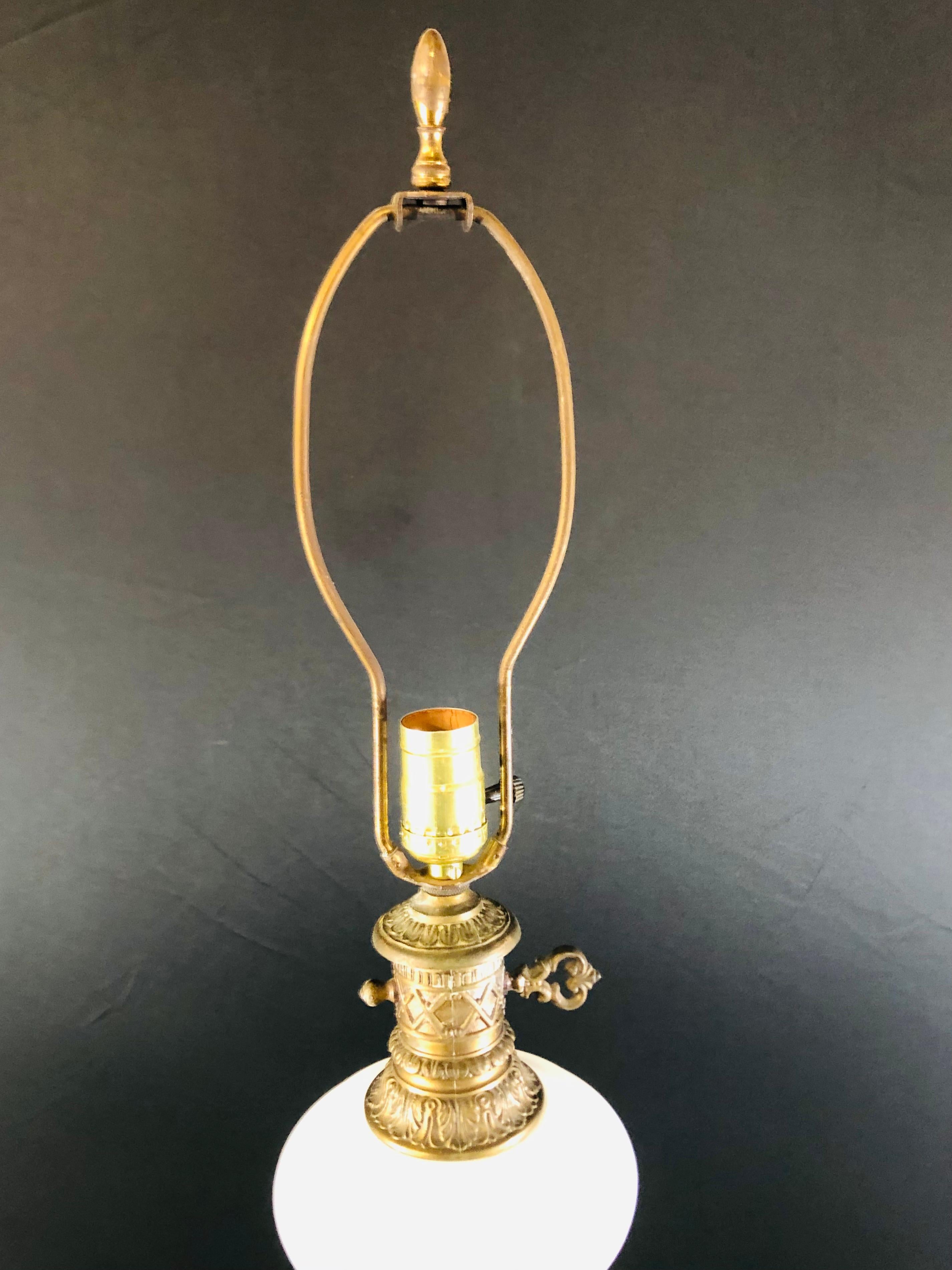 An antique French Louis XVI style table lamp with white opaline glass and bronze inlay and base. The bronze base if finely carved in a triangle shape with three crowfeet and leaves design on top holding the white opaline glass lamp body. A charming