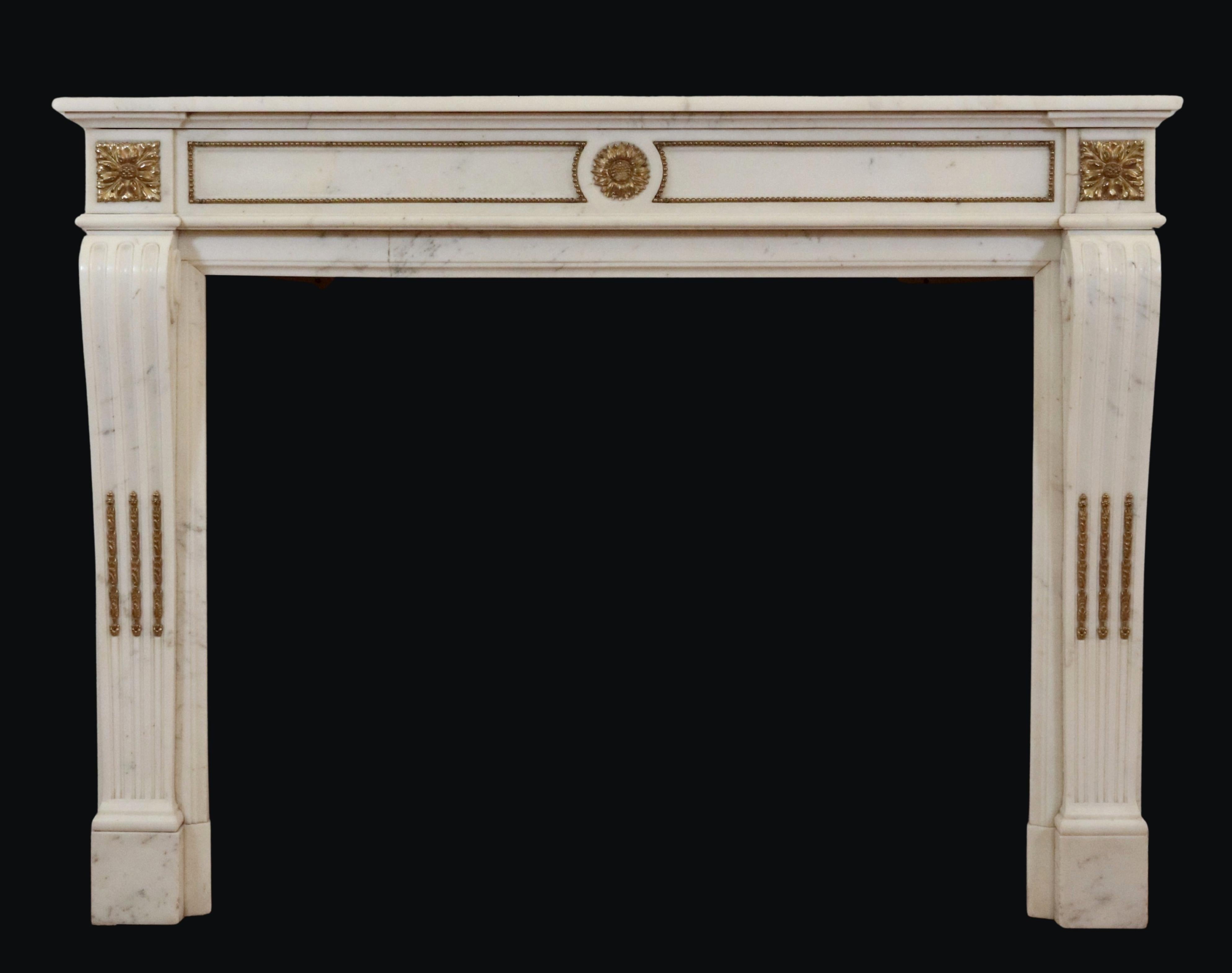 Antique Louis XVI style white marble mantel with light gray veining. Three bronze ormulu floral motifs modestly adorn the face of the surround, while the rectangular panels between the floral motifs are framed in a classic, beaded bronze detail.