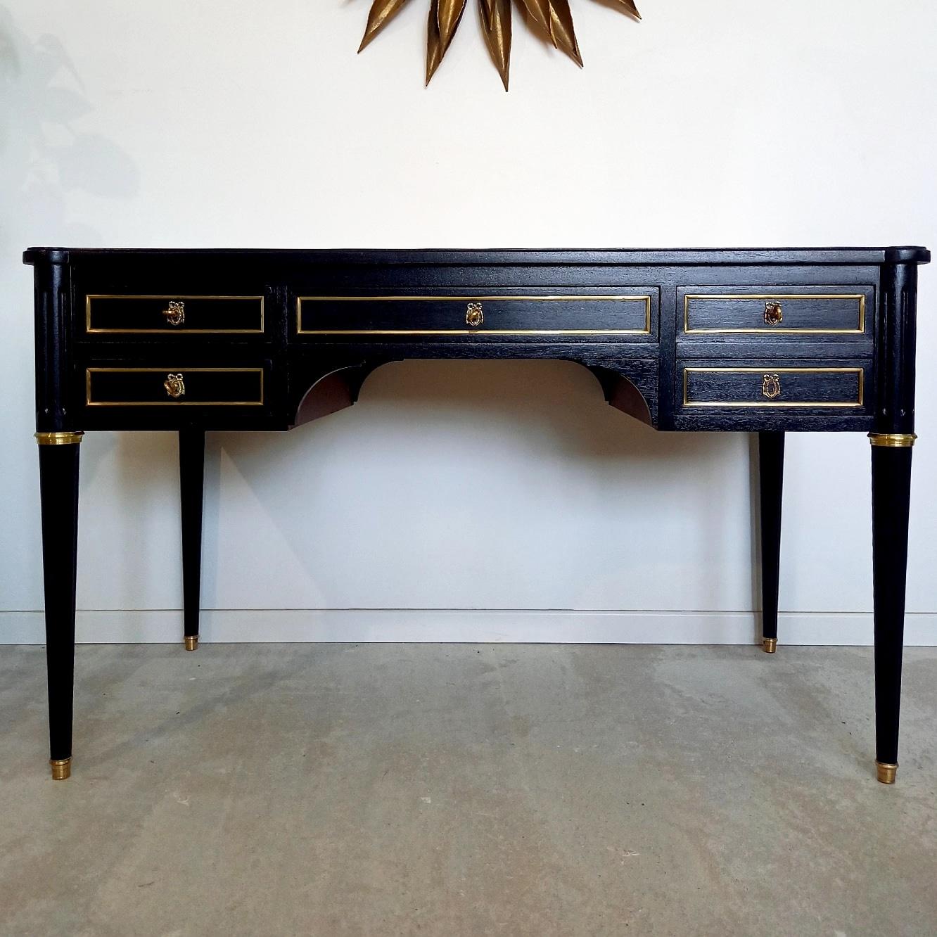 Antique Louis XVI style desk from the 20th century, with cognac leather top and gold embossed frieze.
The front of the piece has four dovetail drawers with brass details. The right double drawer is actually a single deep drawer with a secret hiding