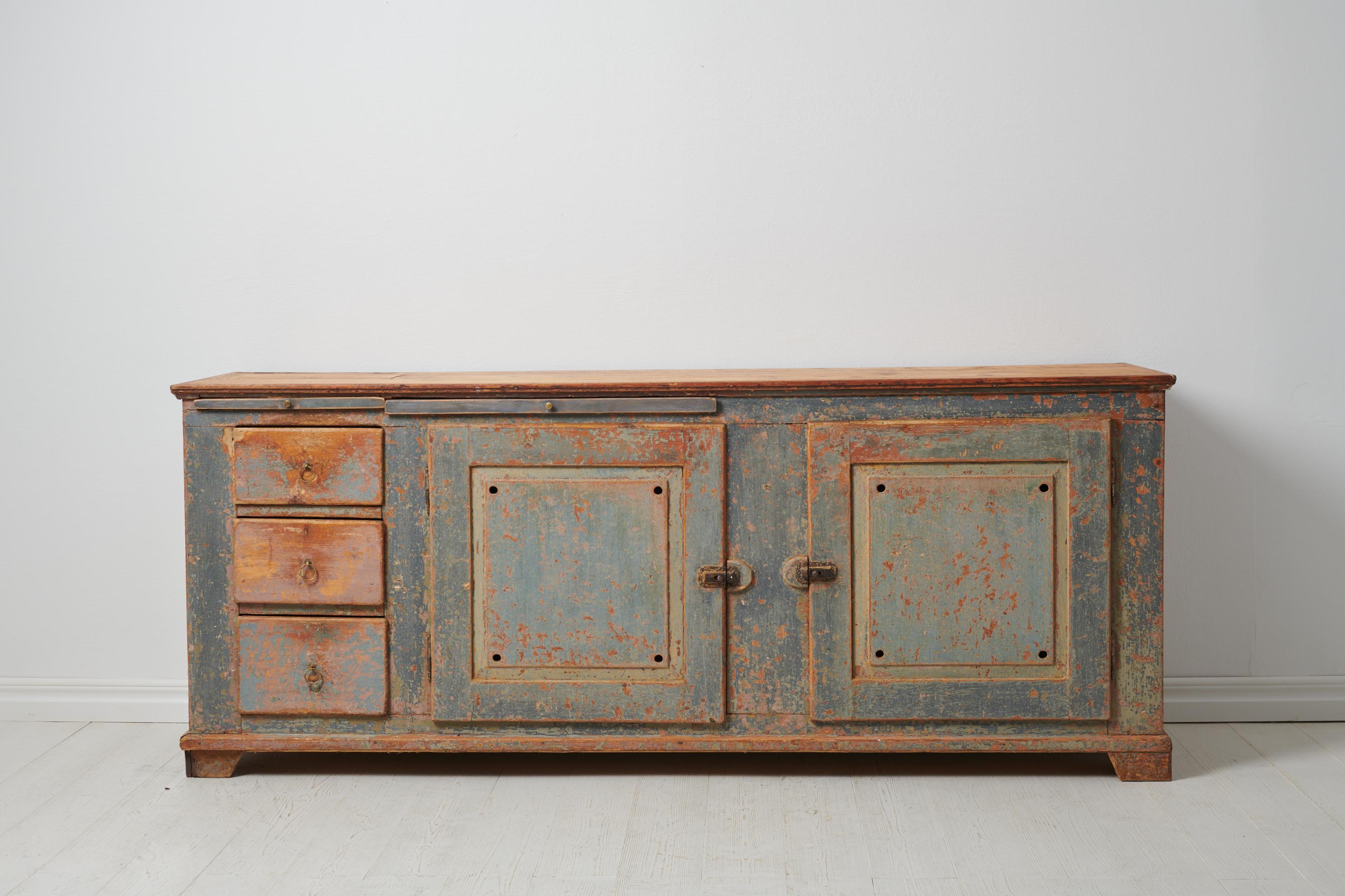 Low and wide genuine sideboard from the mid 1800s. The sideboard is a genuine Swedish country house furniture made in painted pine. It has been dry scraped by hand down to old historic paint. Genuine rustic surface with traces after use. The table