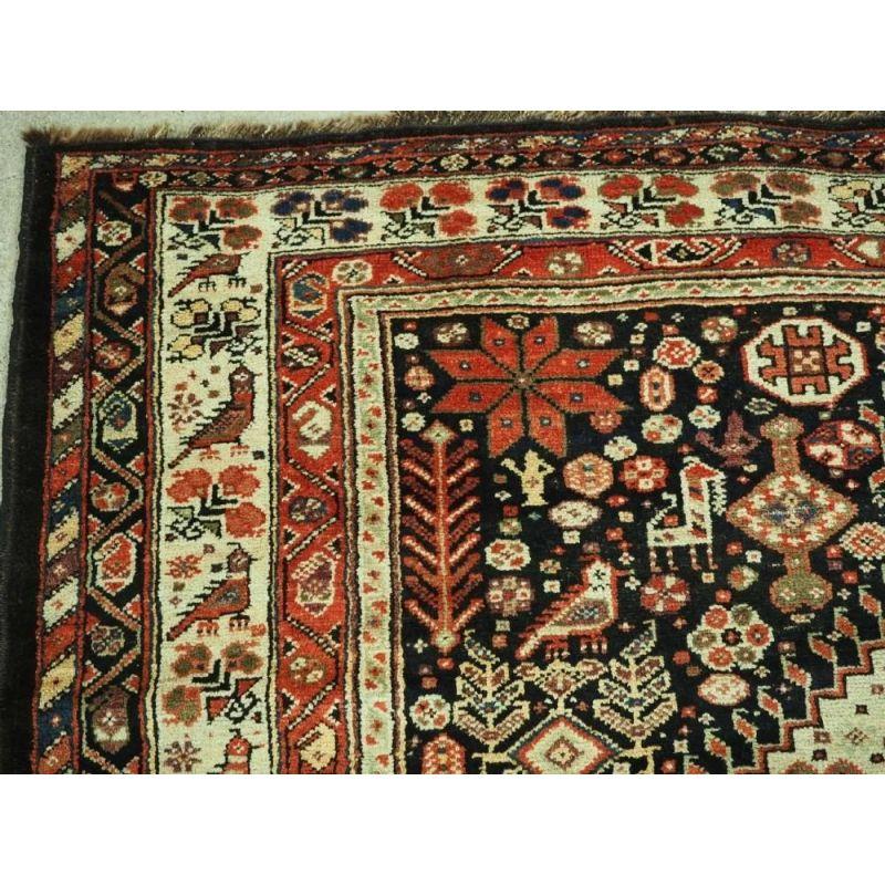 This carpet is an excellent example of Luri tribal weaving, with three linked medallions on a dark indigo blue field. The carpet is completely covered with tribal design elements including birds, animals, people, urns, flowers, shrubs, trees and