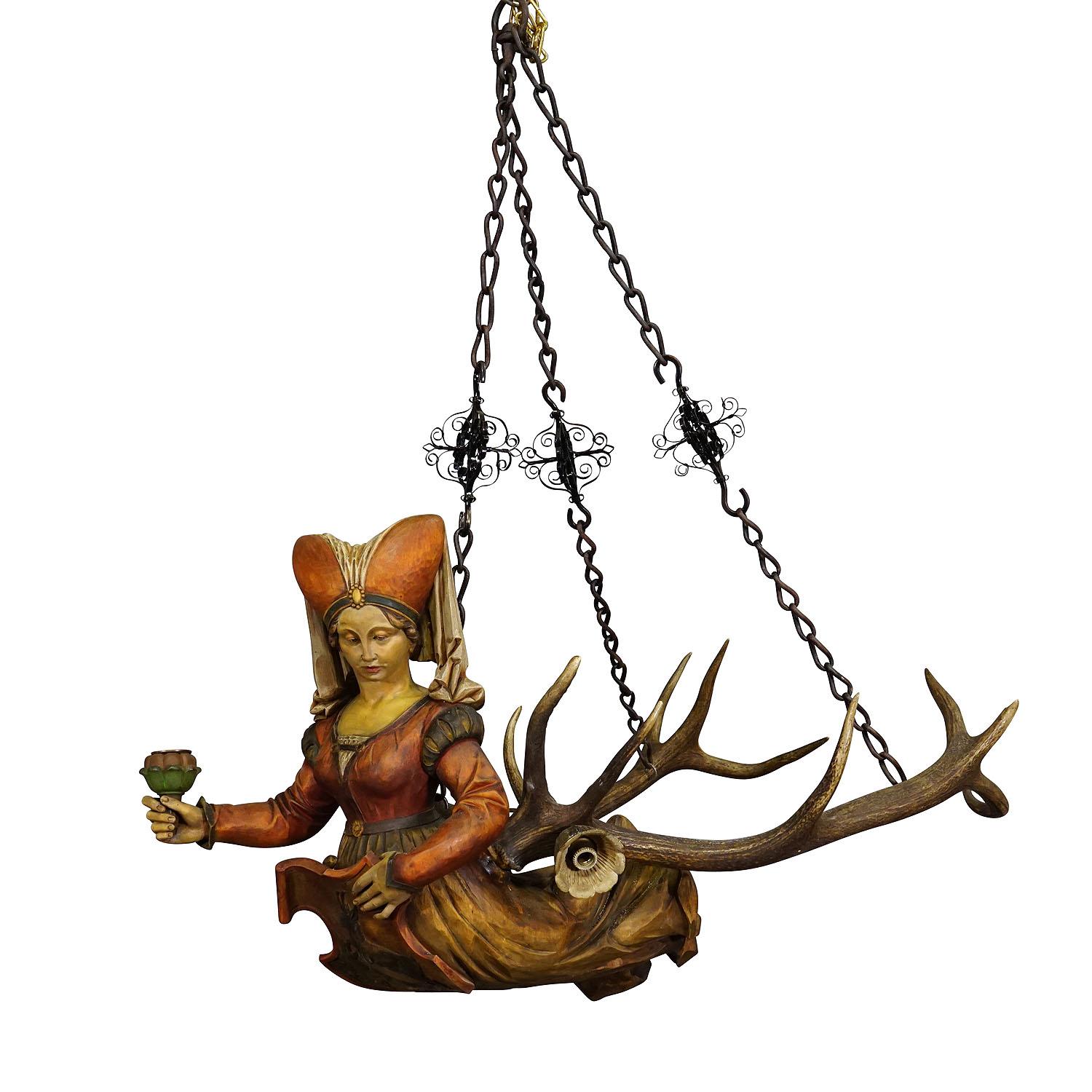 Antique Lusterweibchen of a Medieval Noble Lady ca. 1880s

A great antique chandelier featuring a medieval noble lady holding a heraldic blazon. The sculpture is made of handcarved and painted wood and mounted on a large pair of deer antlers. It
