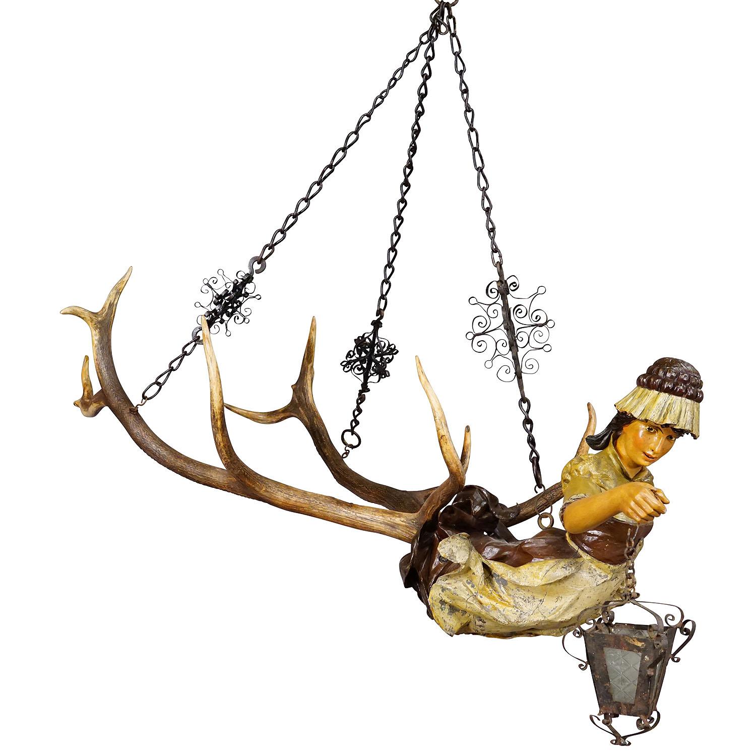 Antique Lusterweibchen of a Patrician Lady ca. 1890

An antique lusterweibchen chandelier of a medieval patrician lady holding a handforged latern. The luster is made of wood with a handpainted finish and mounted on a large pair of deer antlers. It