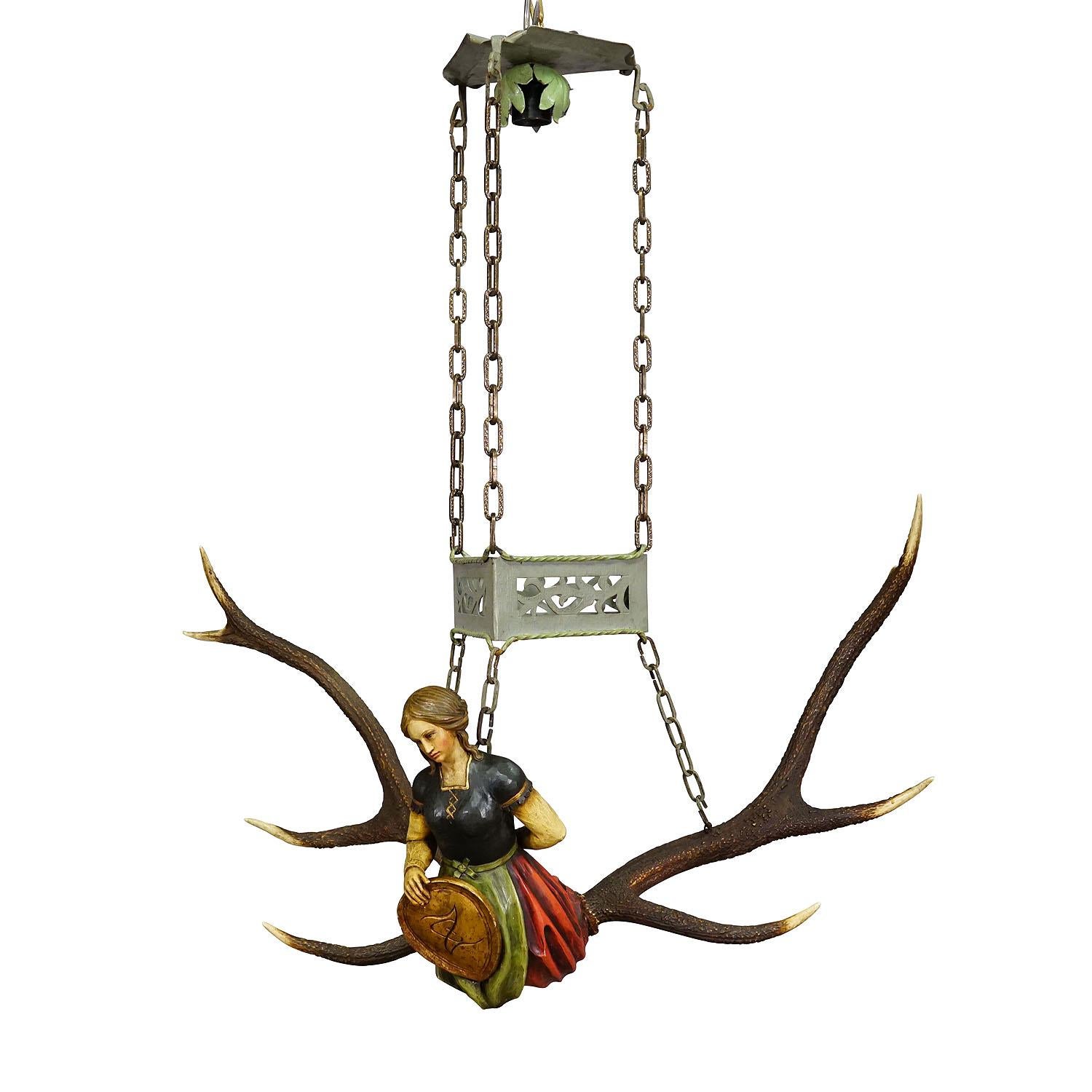 Antique Lusterweibchen of a Victorian Lady ca. 1920

A lovely antique lusterweibchen chandelier of a victorian noble lady holding a blazon. The sculpture is made of handcarved and painted wood and mounted on a large pair of deer antlers. It comes