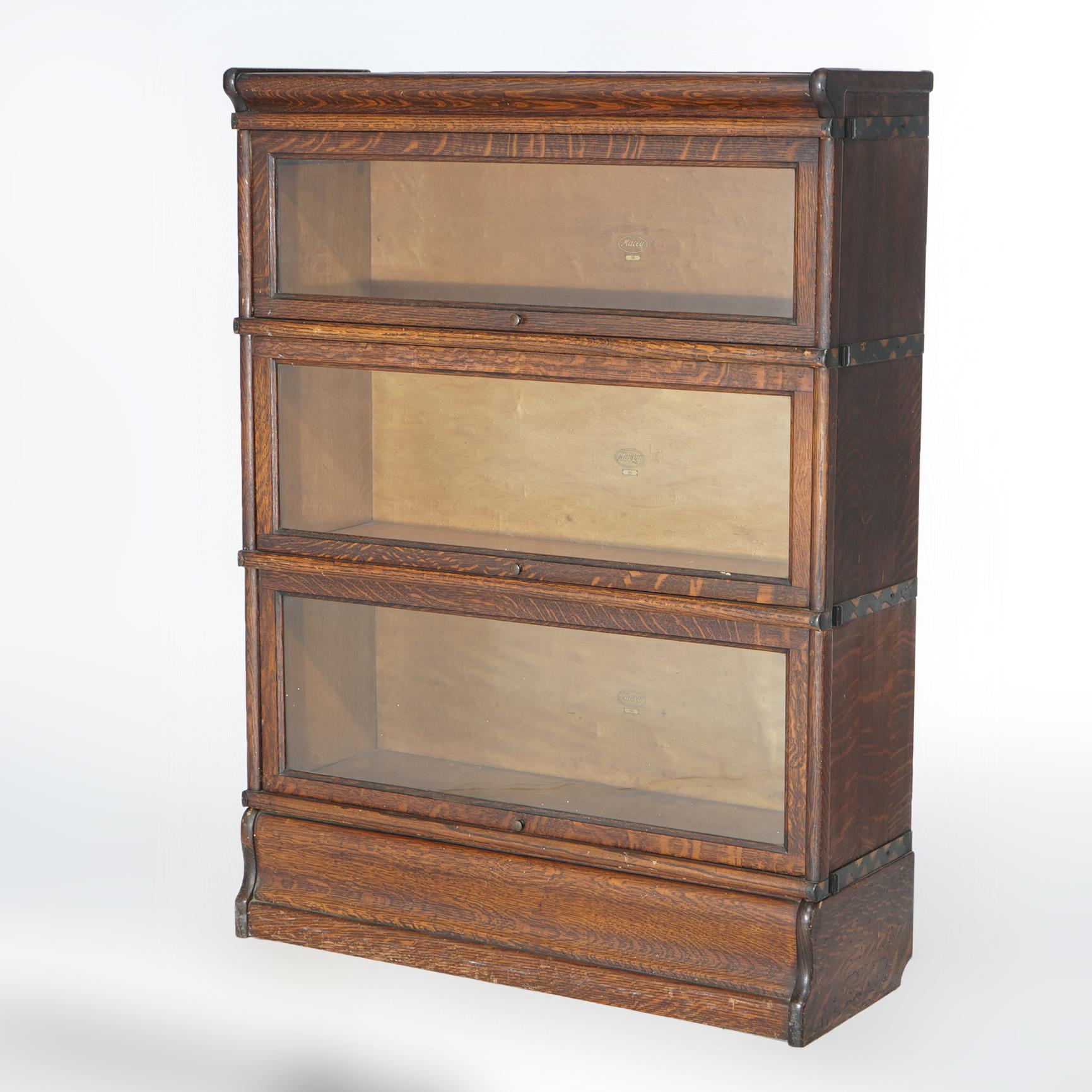 An antique  Arts and Crafts barrister bookcase by Macey offers quarter sawn oak construction with three stacks, each having pullout glass doors, and raised on ogee base, c1910

Measures - 46