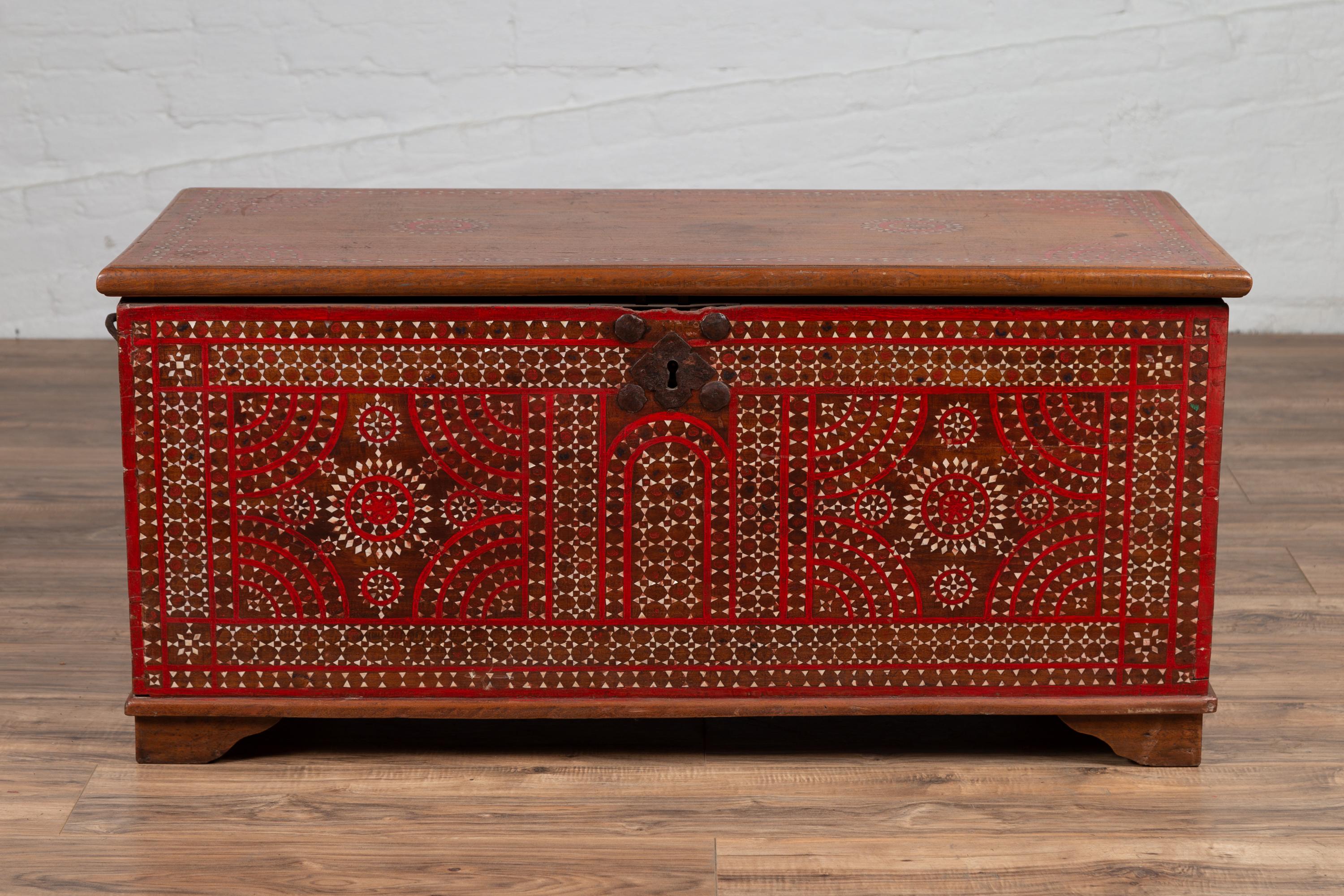 An antique 19th century Indonesian blanket chest from Madura, with red and brown accents and mother-of-pearl inlay. Born on the island of Madura off of the northeastern coast of Java, this exquisite blanket chest attracts our attention with its