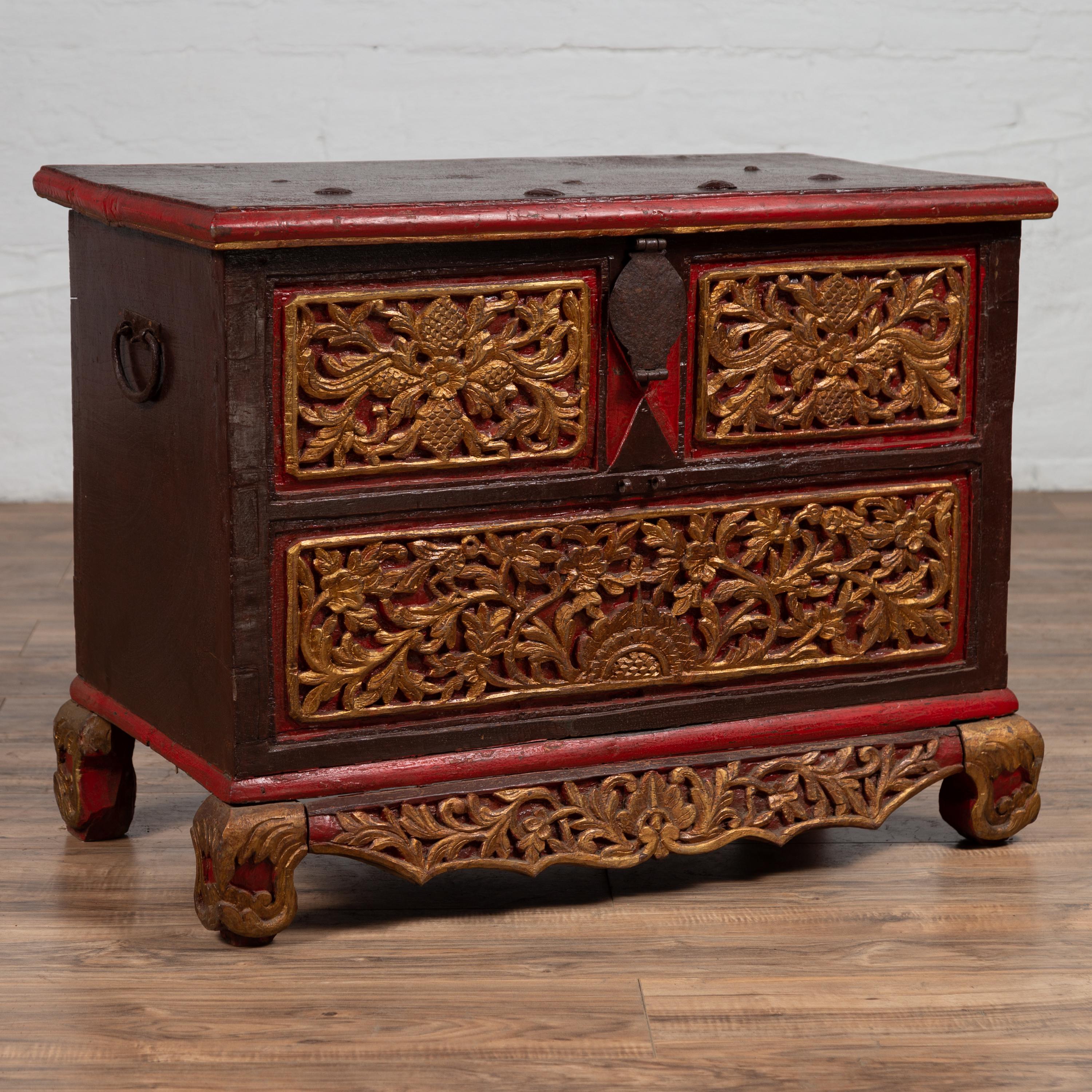An antique Indonesian floral carved wooden blanket chest from the 19th century, with red, brown and gilt accents. This 19th-century Indonesian blanket chest from Madura, an island off Java, is a remarkable artifact that brings both artistic flair