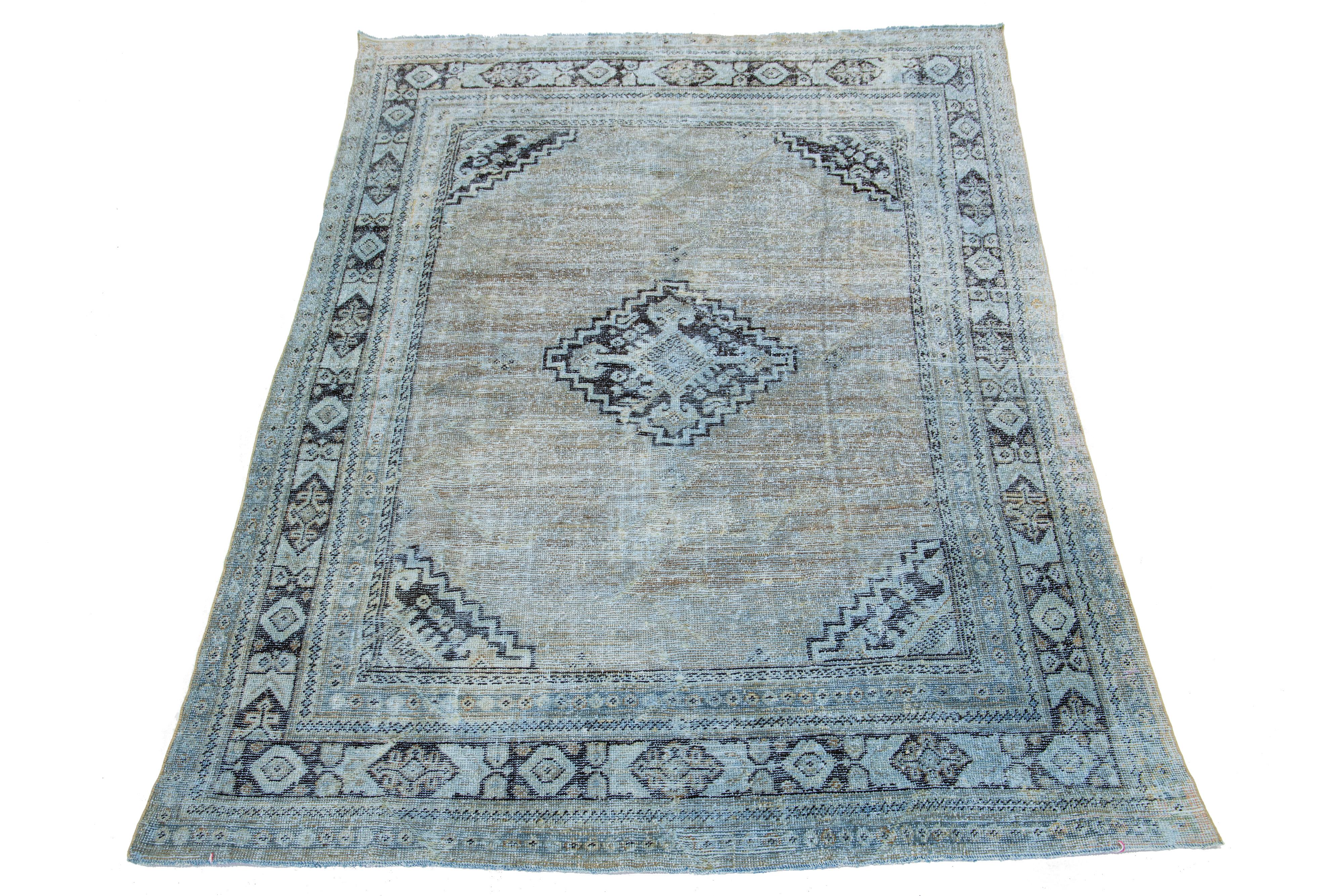 This antique wool rug from the 1920s showcases expert hand-knotted quality and boasts a medallion floral design. The primary color scheme of this rug is composed of brown tones with complementary hues of blue, resulting in a classic and timeless
