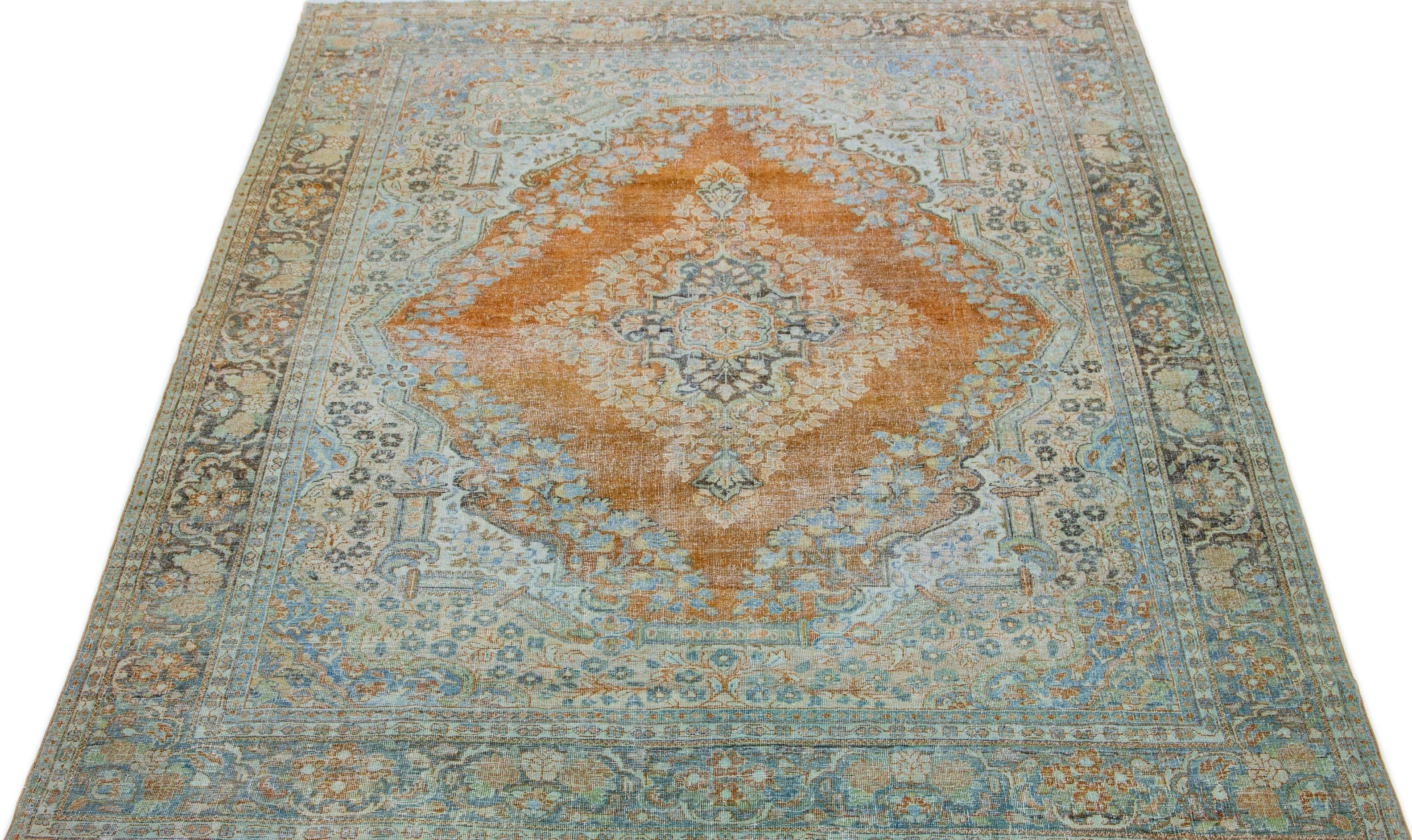This antique wool rug from the 1920s showcases expert hand-knotted quality and boasts a medallion floral design. The primary color scheme of this rug is composed of orange and rust tones with complementary hues of blue, peach, and gray, resulting in
