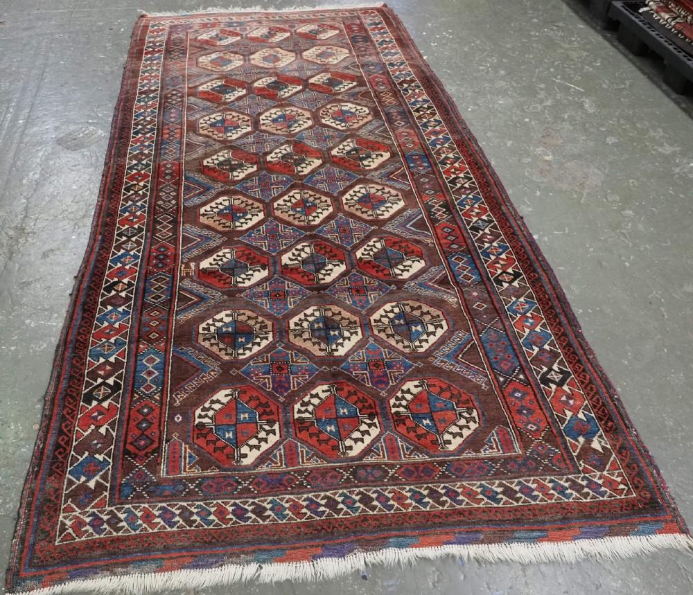 Antiker Belutschen-Teppich, vom Stamm der Mahdad Khani aus der Region Ferdows in Ostpersien
CIRCA 1900

Ein großer Teppich mit drei vertikalen Reihen von neun großen turkmenischen Guls auf einem reichen auberginefarbenen Grund Das großflächige