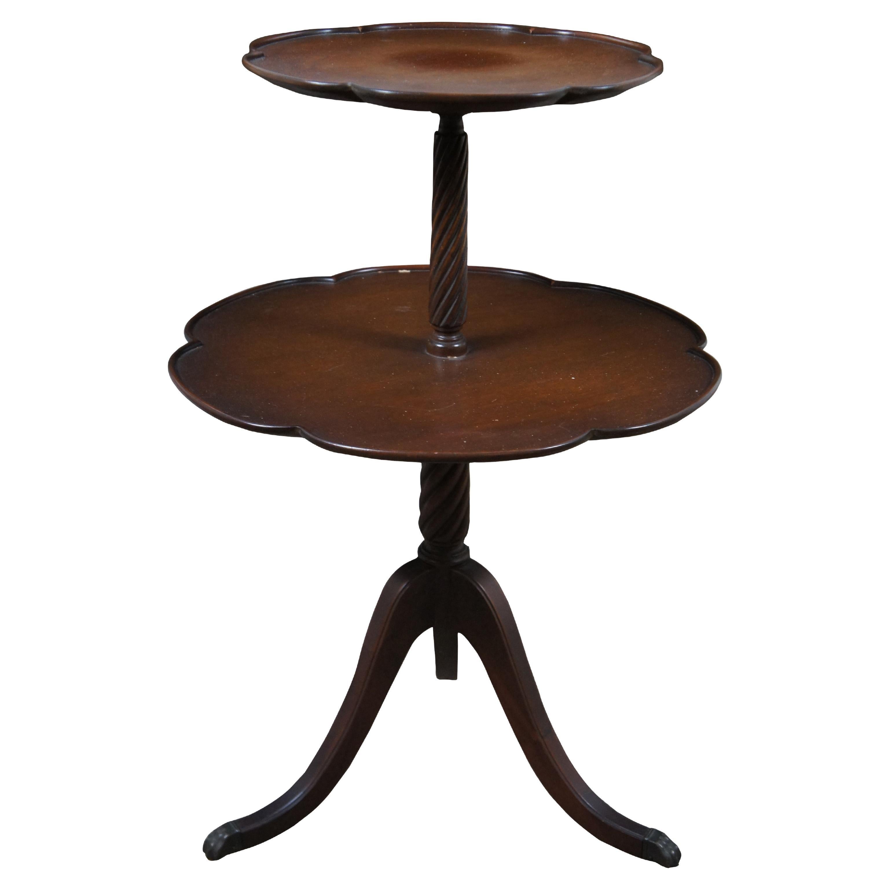 Antique two tier mahogany dumbwaiter side serving table featuring serpentine pie crust edge with turned barley twisted supports and Duncan Phyfe tripod style pedestal base with fluted and flared saber legs and brass capped feet.

Dimensions:
20