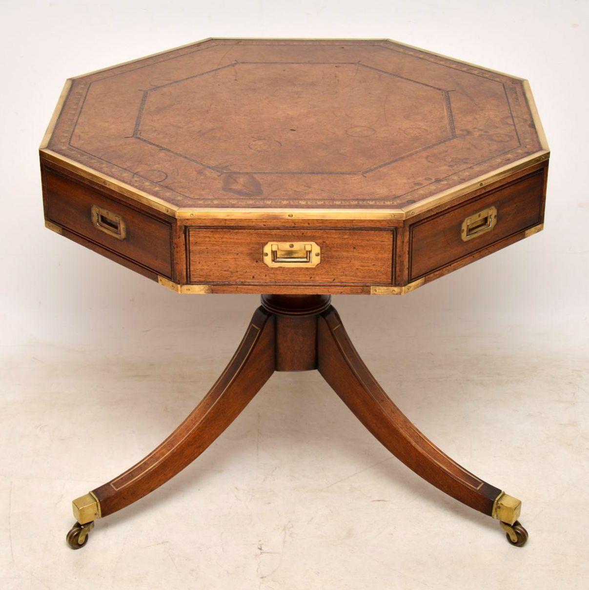 Antique mahogany Campaign style drum table with an octagonal top inset with the original tooled leather which has aged really well and shows plenty of character. The top has a brass top rim, inset brass military handles on the drawers and more brass