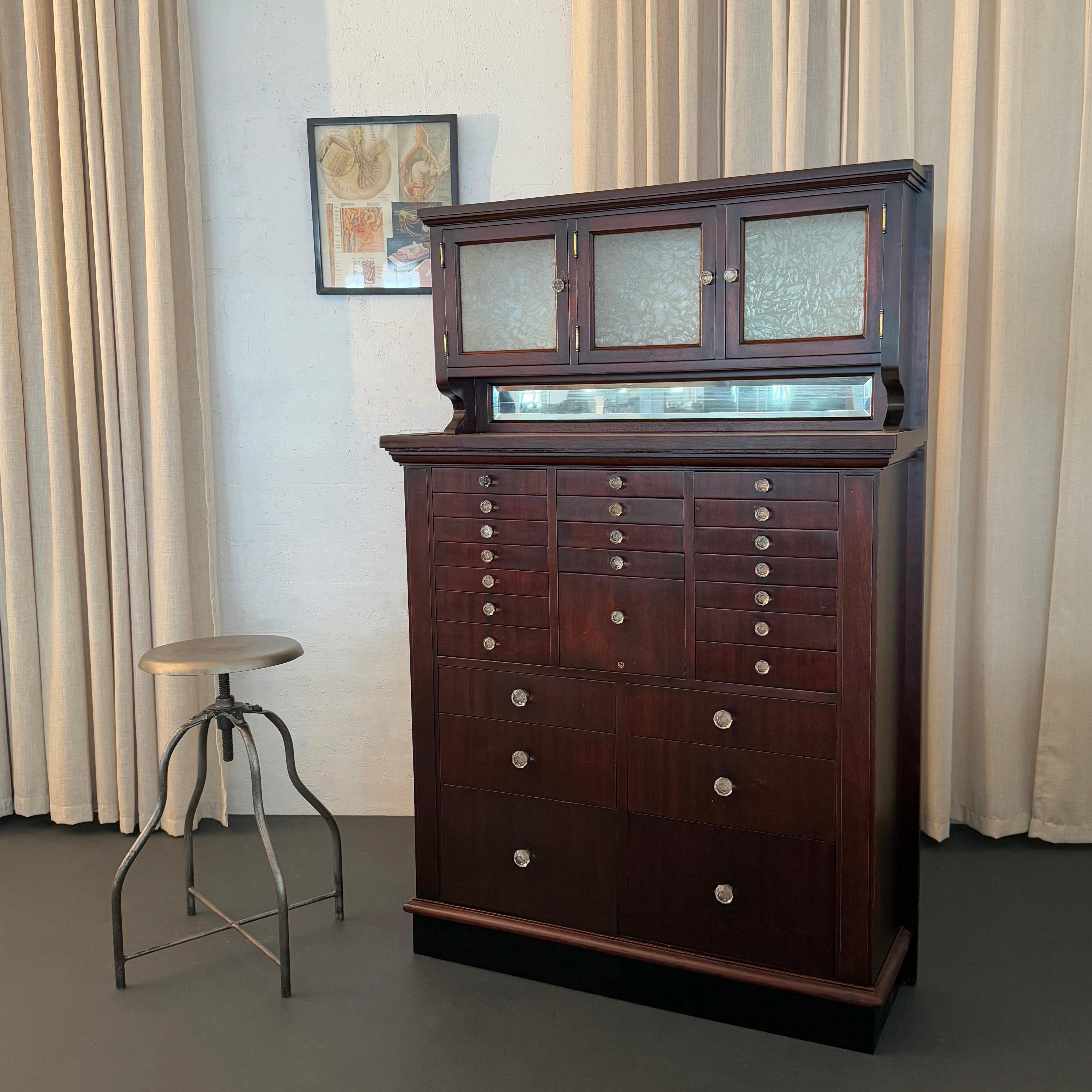This antique mahogany multi-drawer apothecary dentist cabinet was manufactured by the American Cabinet Company in the early 20th century circa 1915. The cabinet features 7