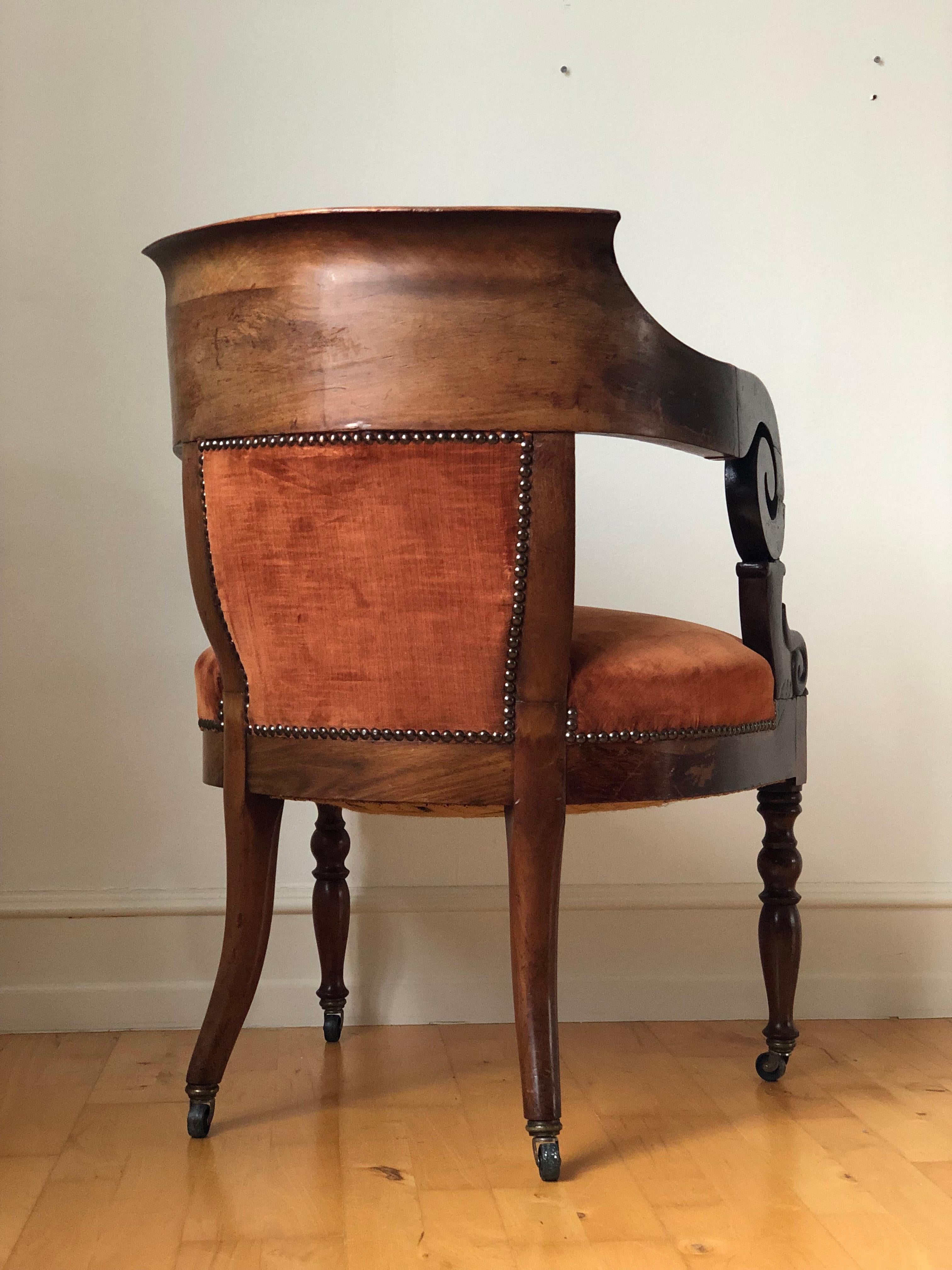 An elegant English armchair from the 1850s, crafted from solid mahogany and finished with burgundy upholstery. Sturdy, comfortable, and timeless, it’s in good condition and stands on sturdy antique casters. Perfect as a statement piece for any home