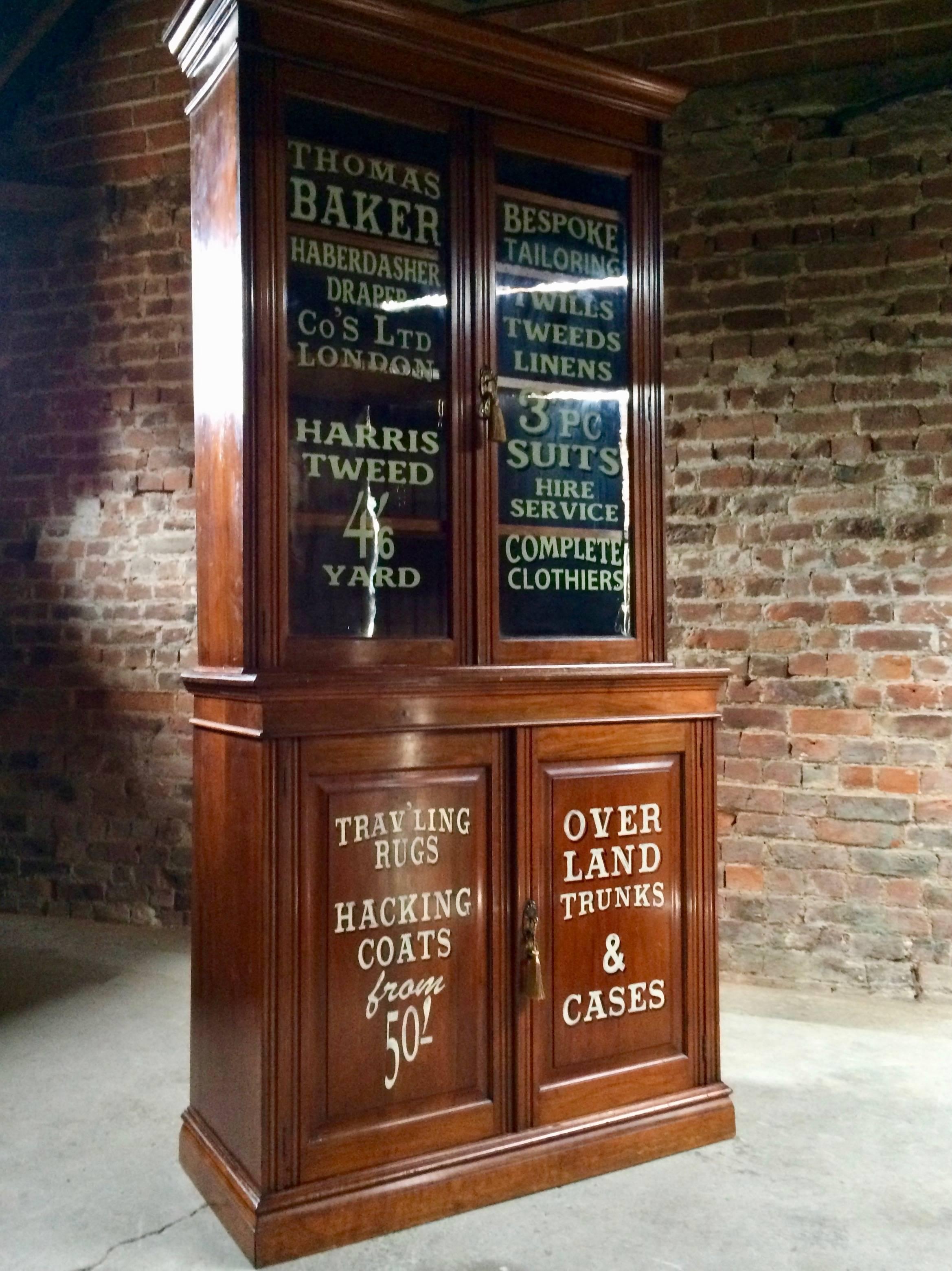 Stunning Edwardian Haberdashery style walnut bookcase on cupboard, circa 1902, corniced top over two glazed doors with four adjustable shelves within above panelled double cupboard, applied later with tailors advertising writing signage, comes with
