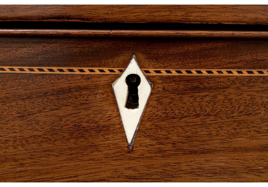 Antique mahogany bow front chest with four drawers having bone diamond form escutcheons and later added oval drop pull handles with embossed flowers. The chest with cross banding and an intricate striped inlay around the perimeters of the drawers