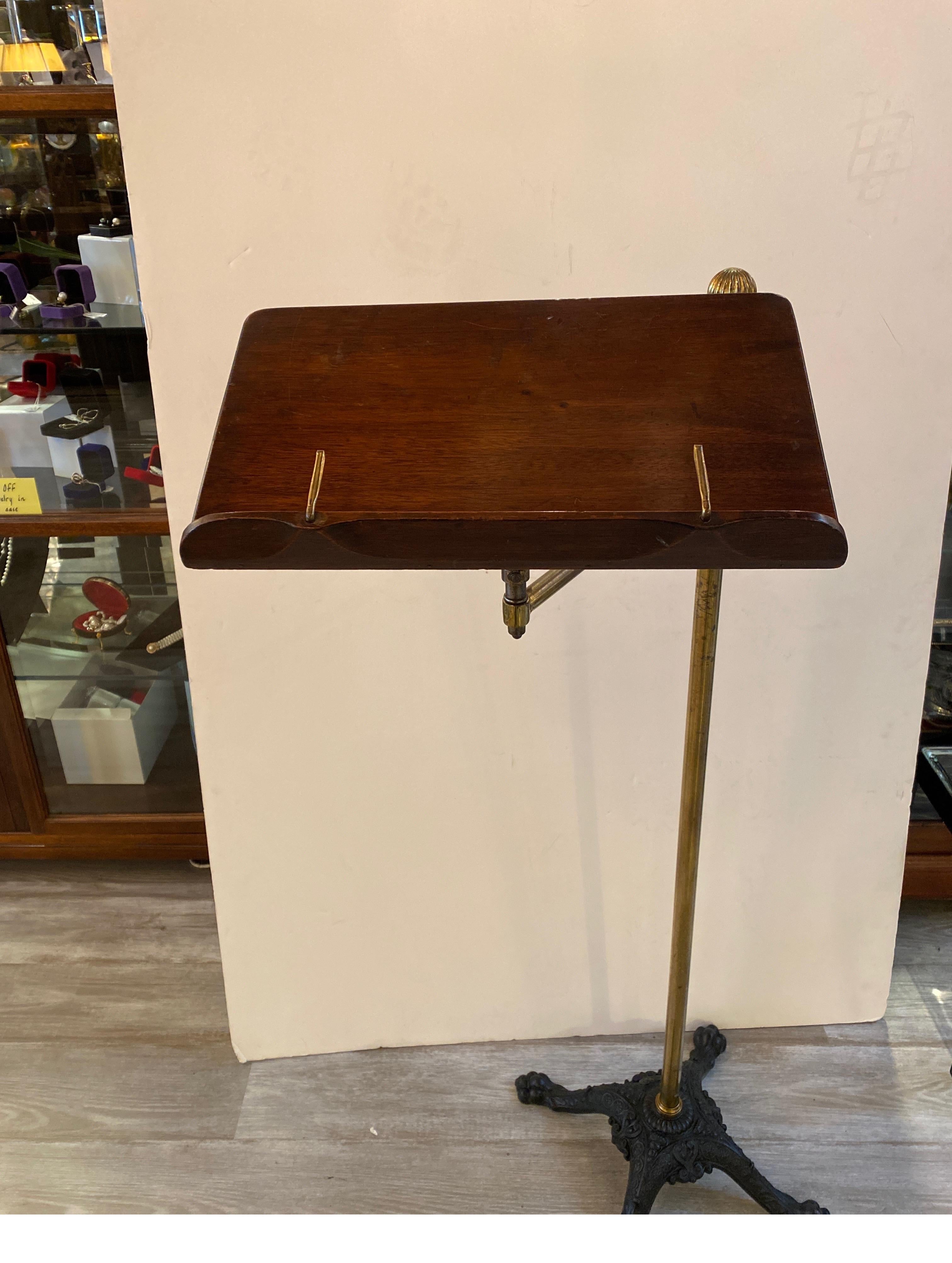 An Antique adjustable Lectern with mahogany shelf attached to a brass pole which is adjustable supported by a cast iron paw foot base.
