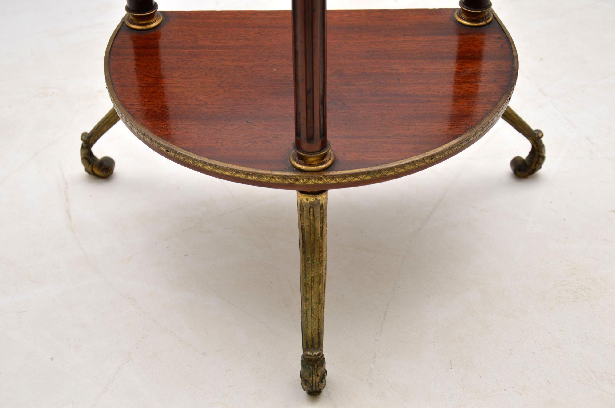 Nicely designed French antique mahogany two-tiered side table or stand. In fact some might call this an étagère. The two levels have brass edgings and the brass legs are very decorative. The three columns in the middle are fluted. I would date this