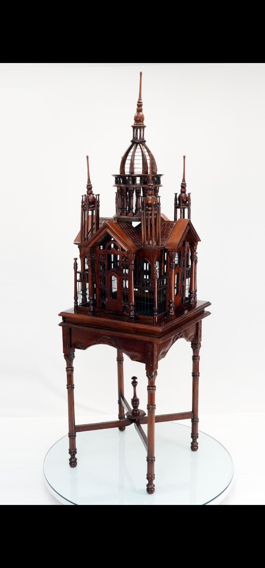 Over 6 feet tall.
RARE petite monumental birdcage.
Mahogany birdcage with stunning architectural features on a table/ base. 
Pull out tray for cleaning.
4 doors.
5 spires.
Striking in any room.
Conversation piece.
Rare petite architectural bird cage