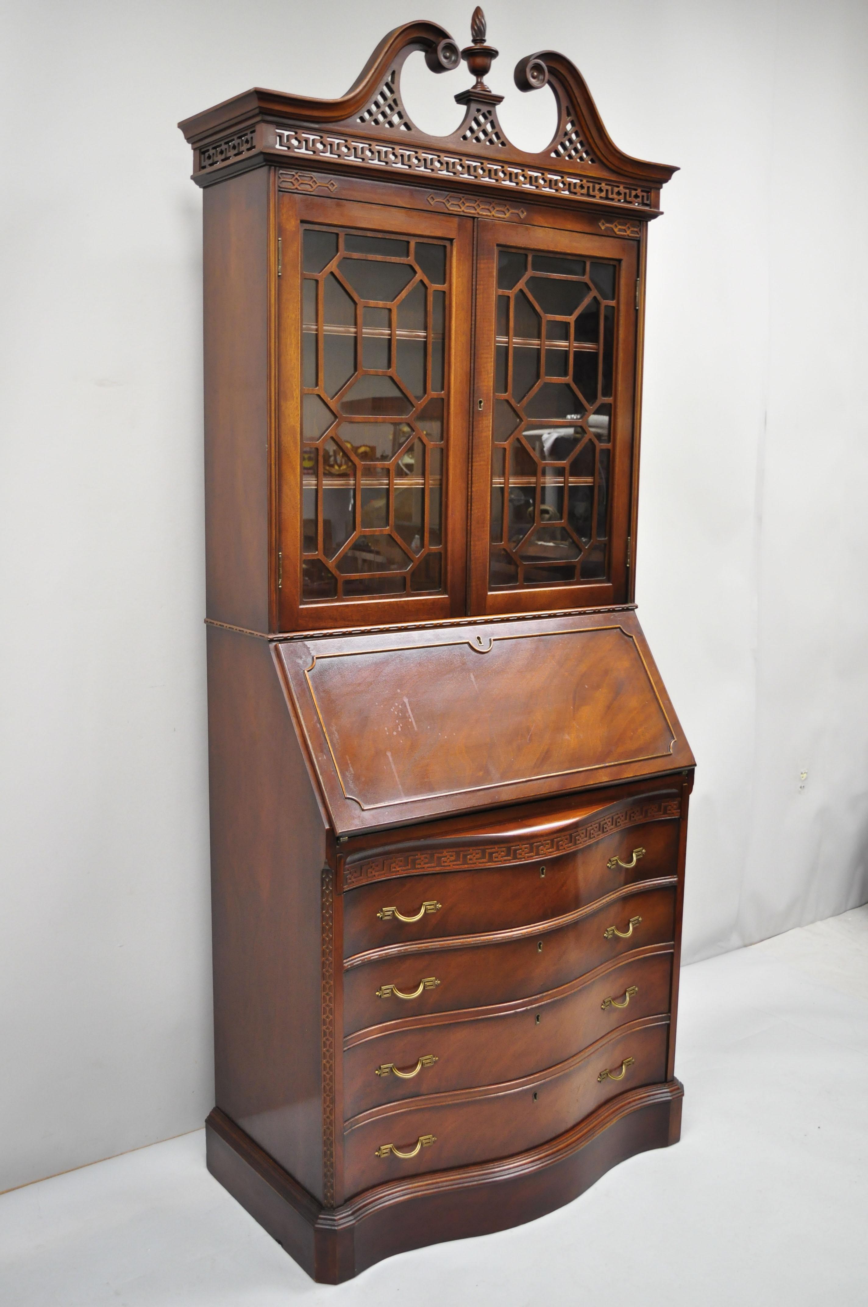 Antique mahogany Chinese Chippendale carved fretwork bookcase secretary desk. Item features pierce carved fretwork broken arch pediment, fitted interior, bow front, spiral carved finial, beautiful wood grain, nicely carved details, 2 glass swing
